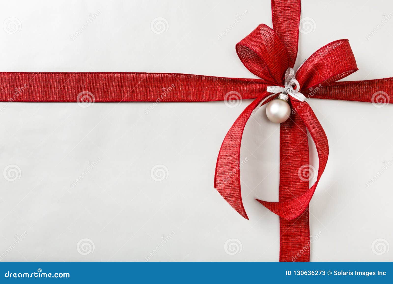 beautiful christmas gift present with bright red bow and silver wrapping paper background border