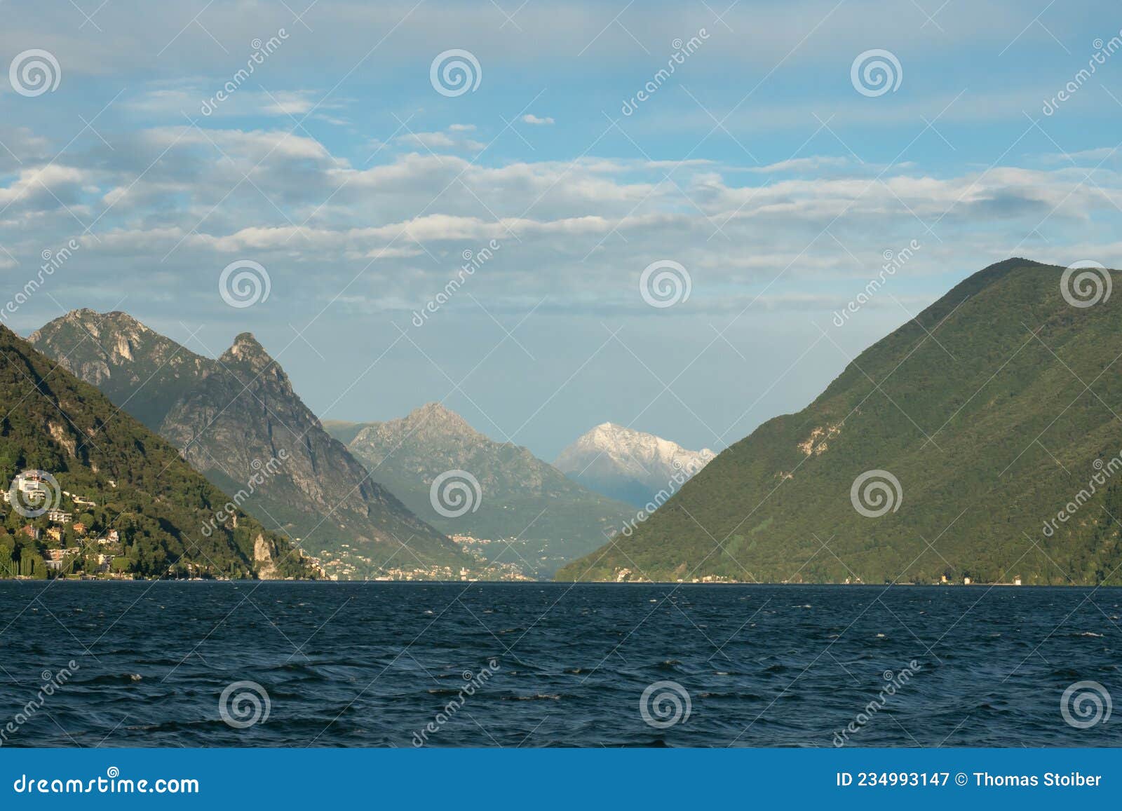 lugano, switzerland - october 6th 2021: lago di lugano with surrounding hills and mountains in the afternoon sunlight.