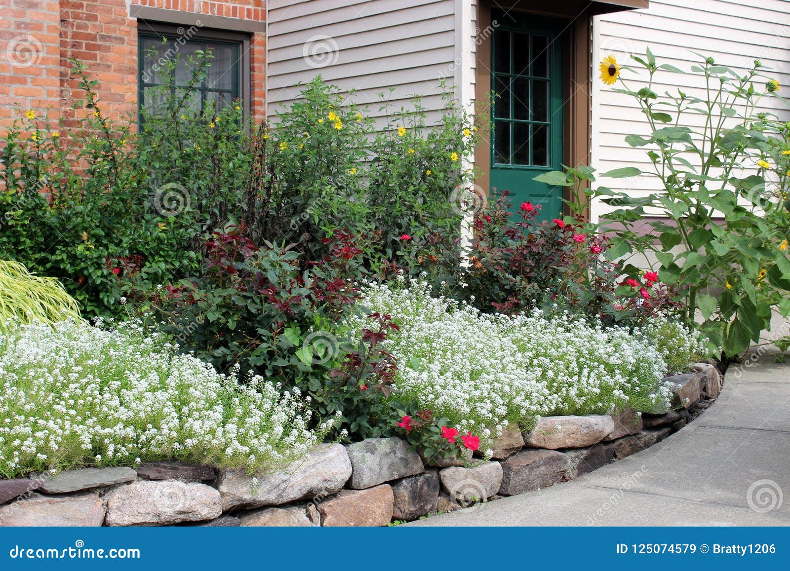 beautiful curbside appeal with stone wall and colorful flowers and