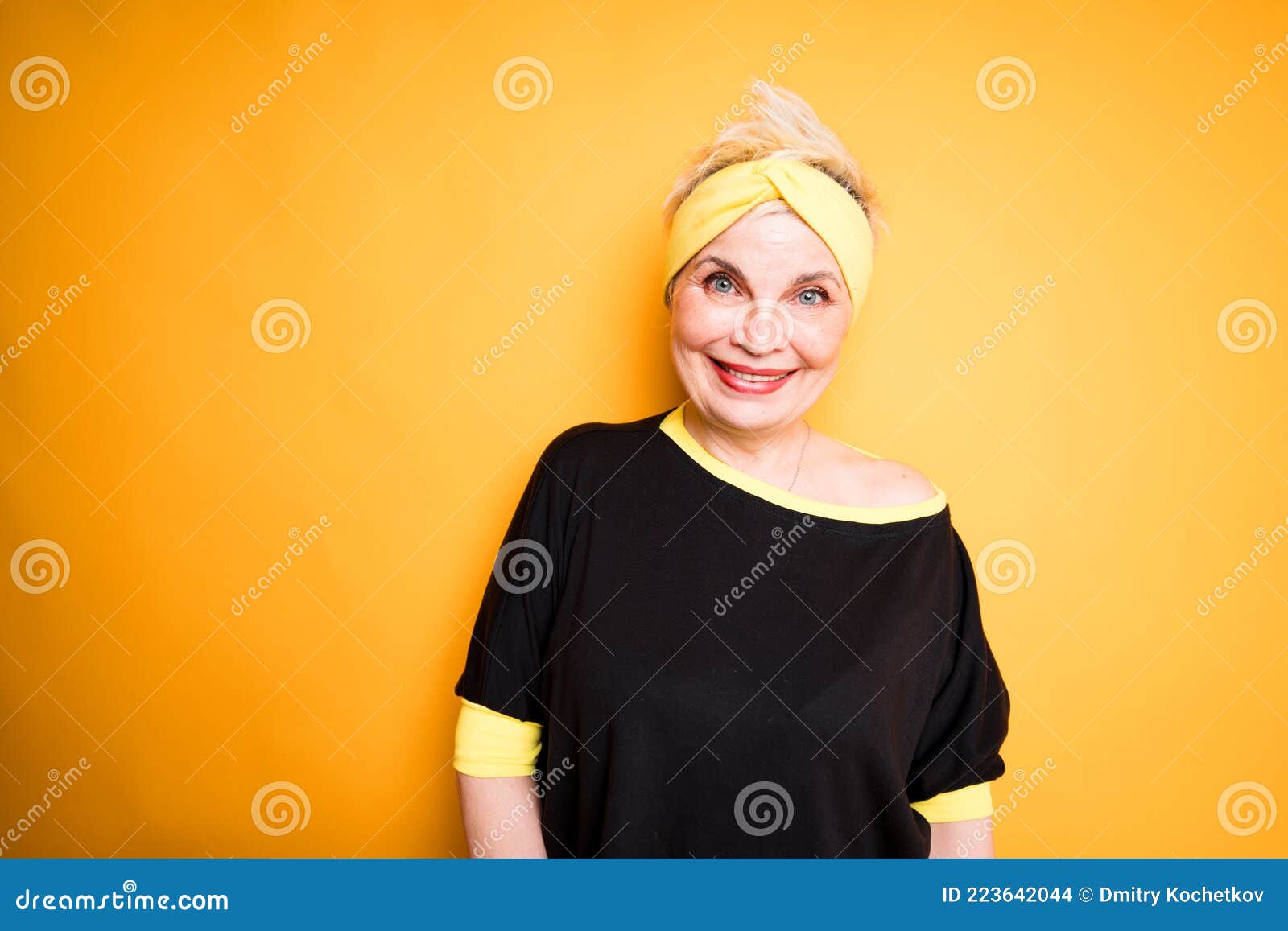 beautiful elderly woman in a sports bandage on her head and in a black t-shirt smiling and getting ready for a workout