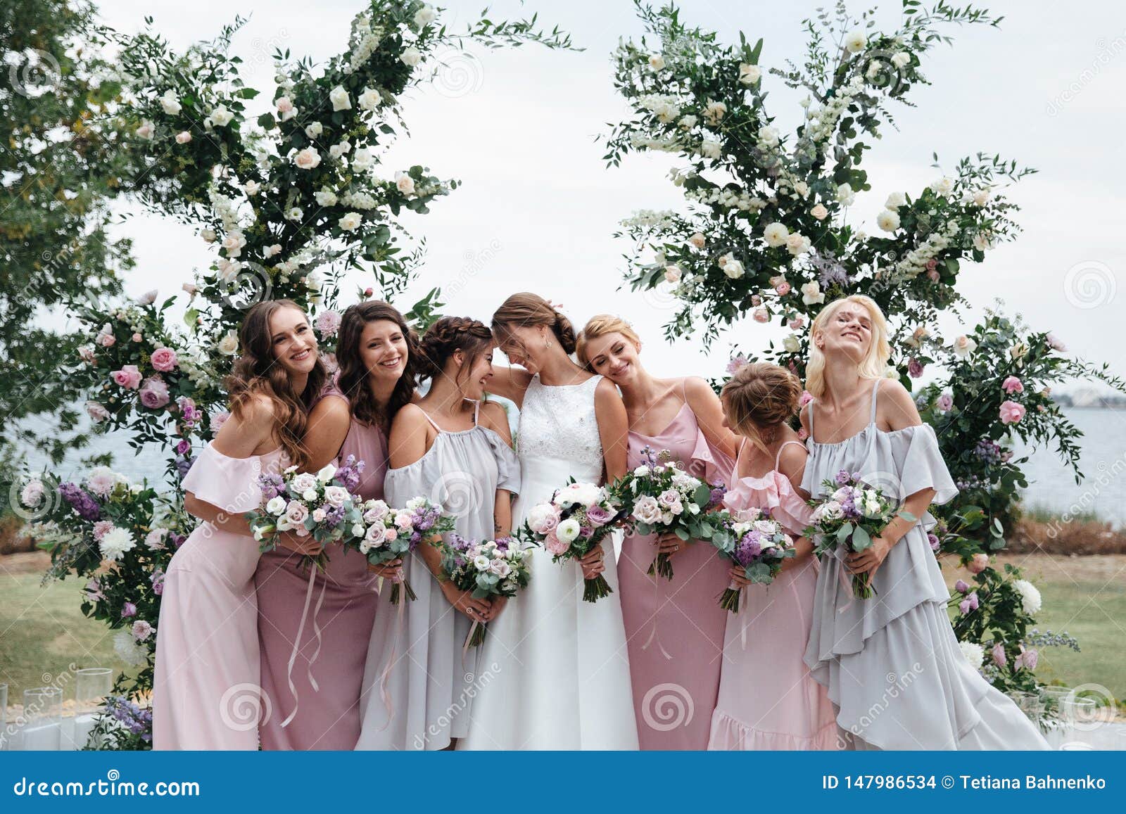 beautiful elegant slim smiling bridesmaids in delicate pink beige summer dress on the wedding ceremony.
