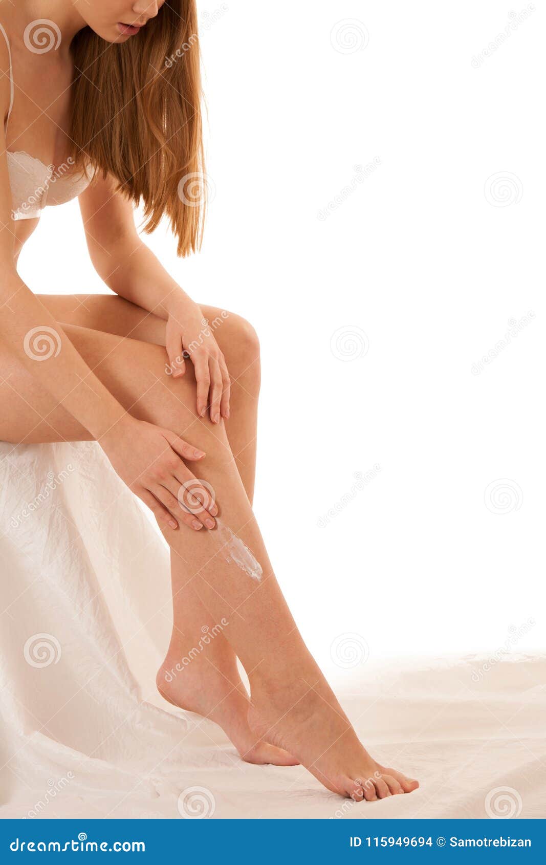 beautiful elegant young woman applying skin cream on her legs is