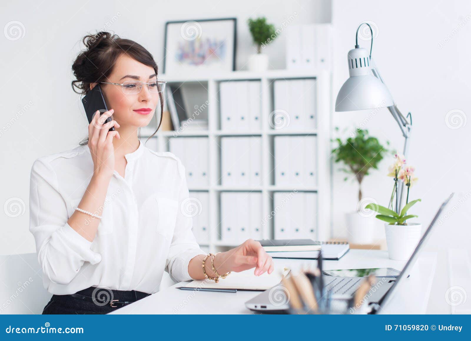 Beautiful Female Assistant Calling Using Cellphone. Young Office Worker