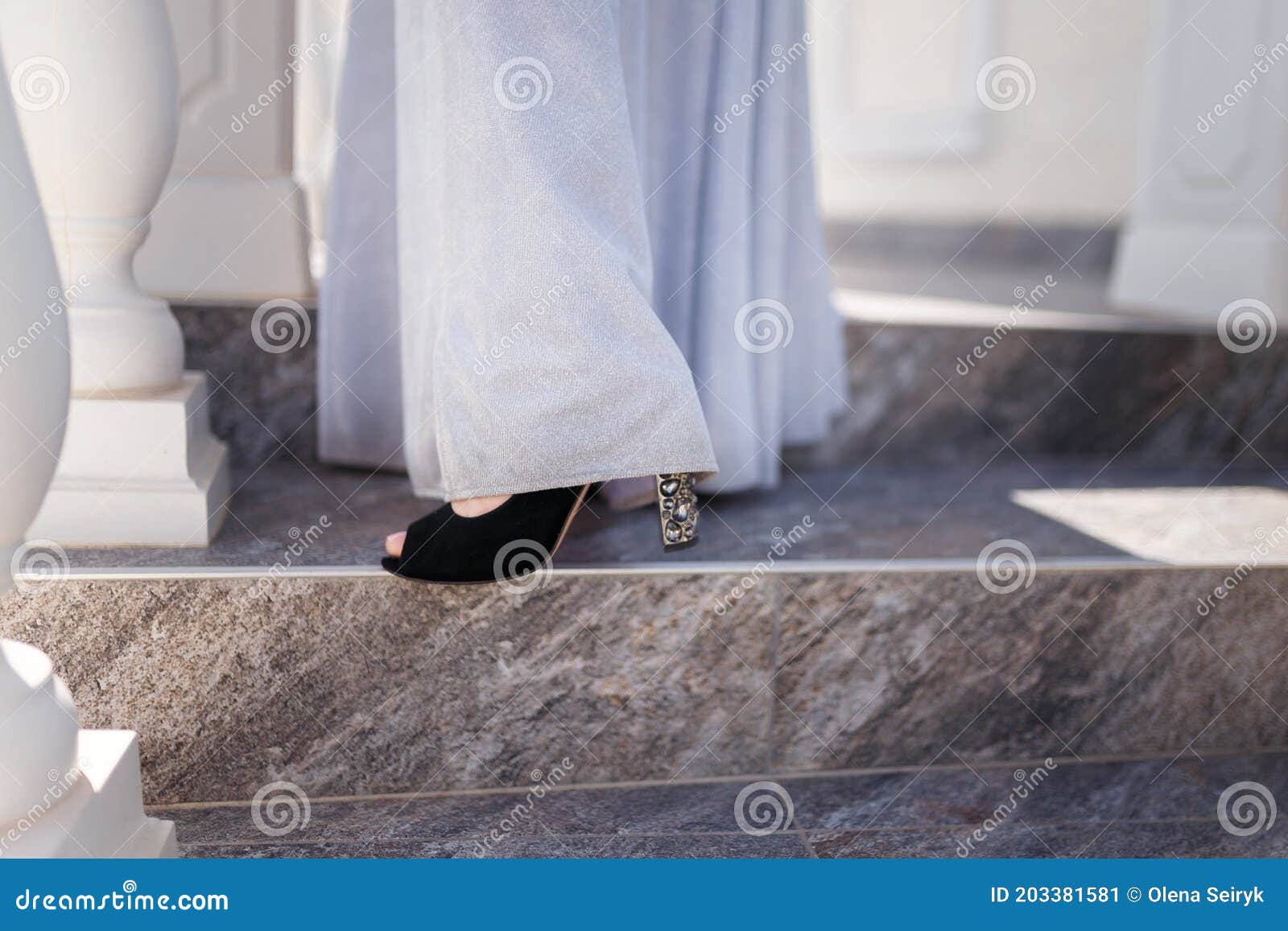 beautiful female feet in high heeled shiny shoes with long tender white dress. school leaver or bride accessories