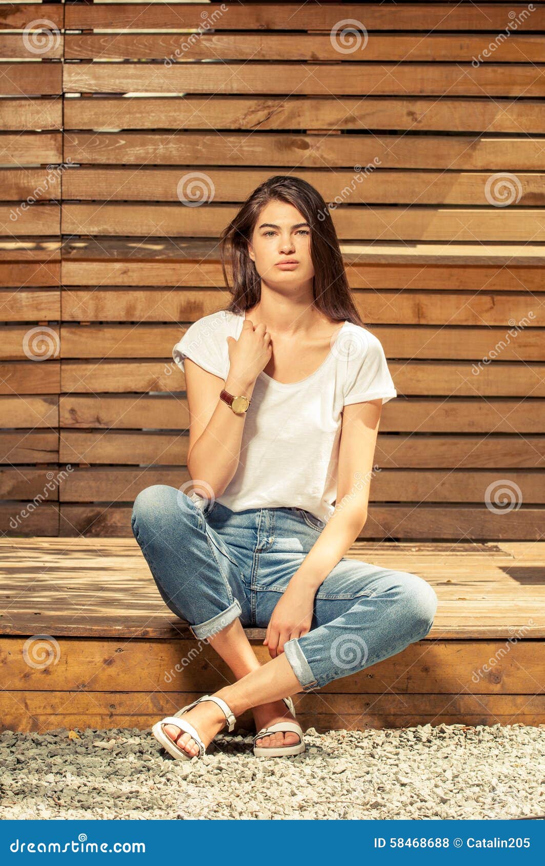 Beautiful brunette girl with long flowing hair dressed in jeans jacket and jeans  poses holding her hands on her head on the dark background in the studio  Stock Photo | Adobe Stock