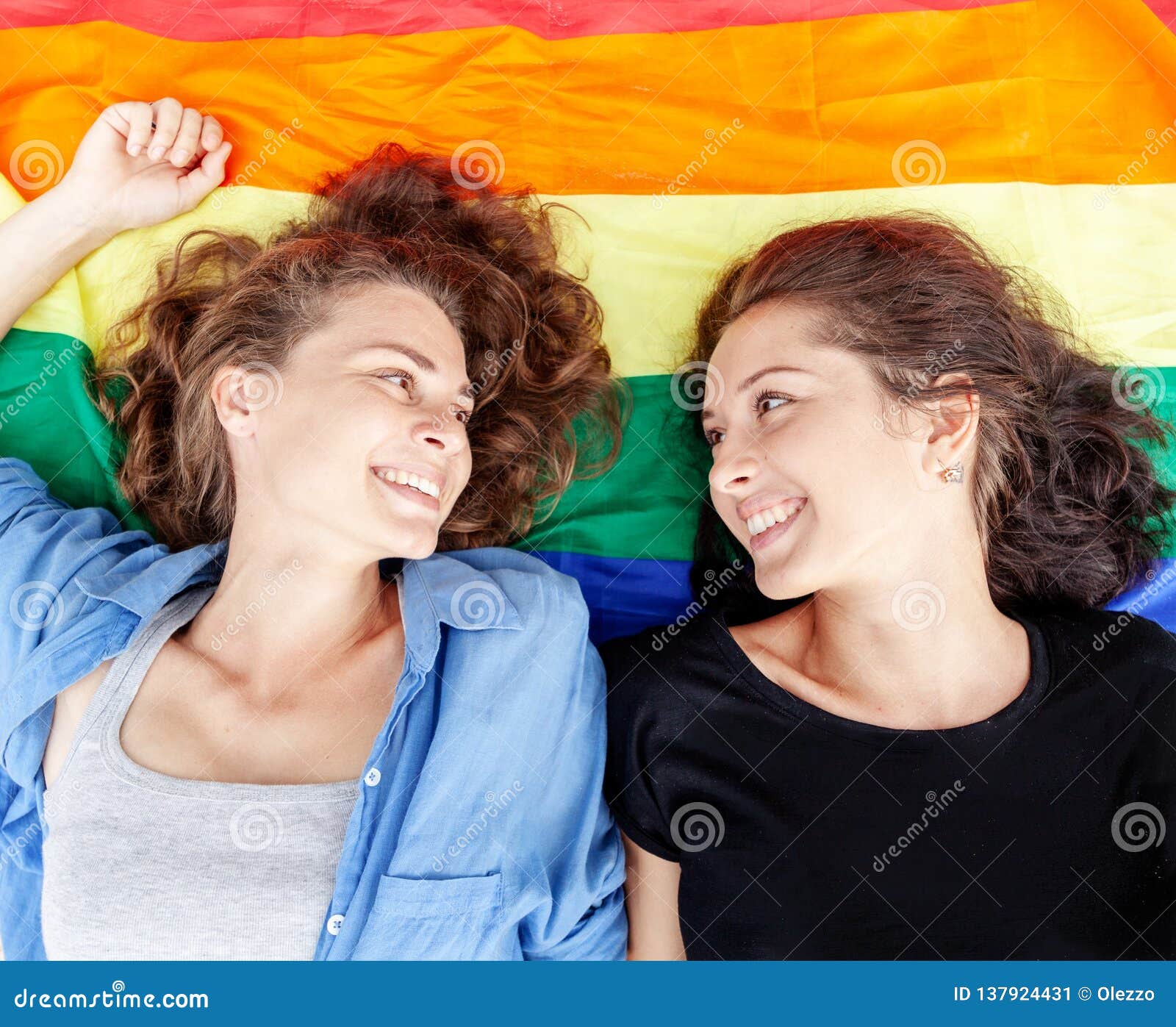 Beautiful Female Young Lesbian Couple In Love Lies On The Rainbow Flag