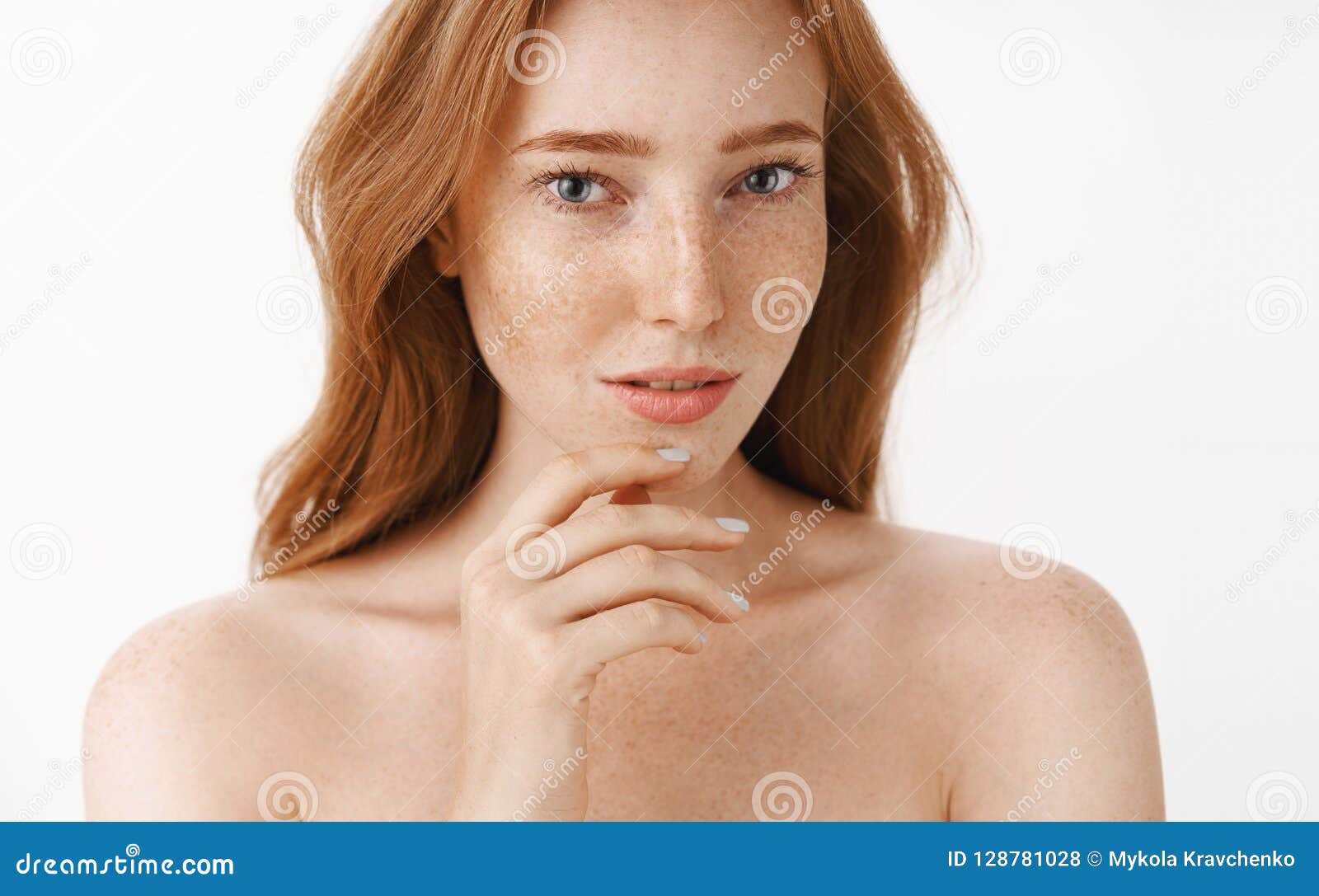 beautiful feminine and attractive woman with natural red hair and freckles on face and body touching chin gently with