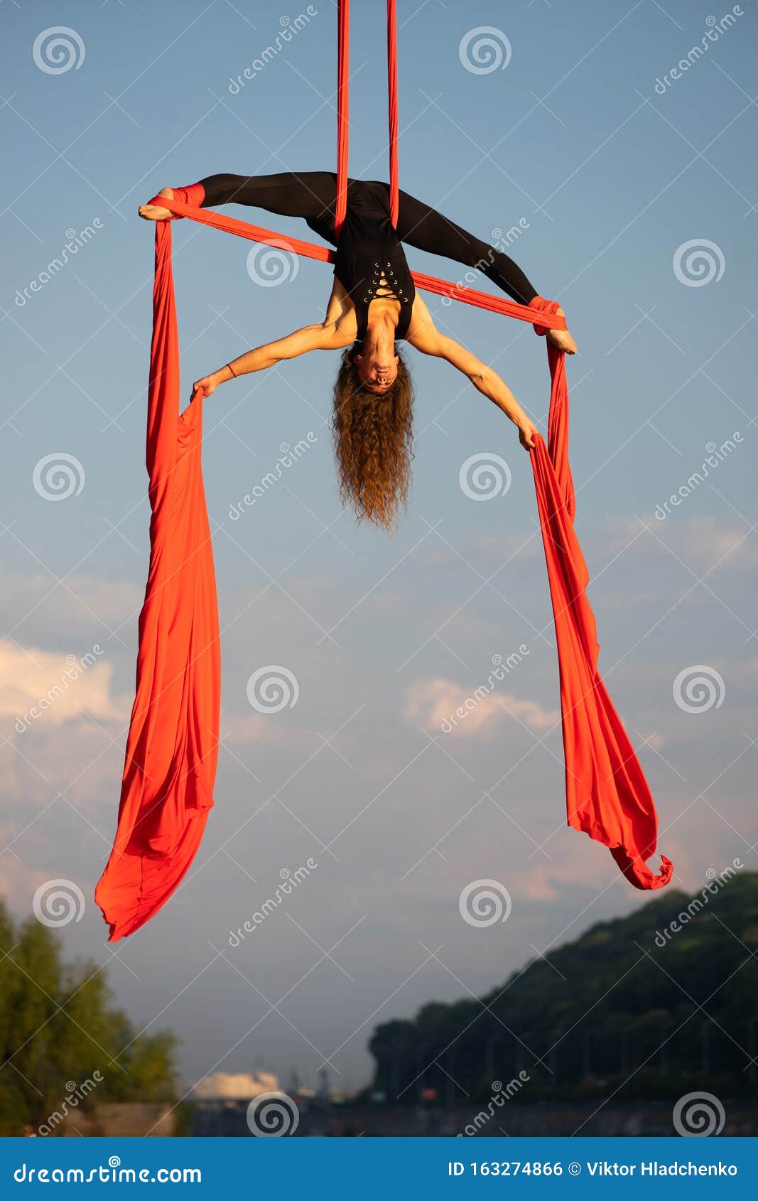 Beautiful And Flexible Female Circus Artist Dancing With Aerial Silk On A Sky Background Stock
