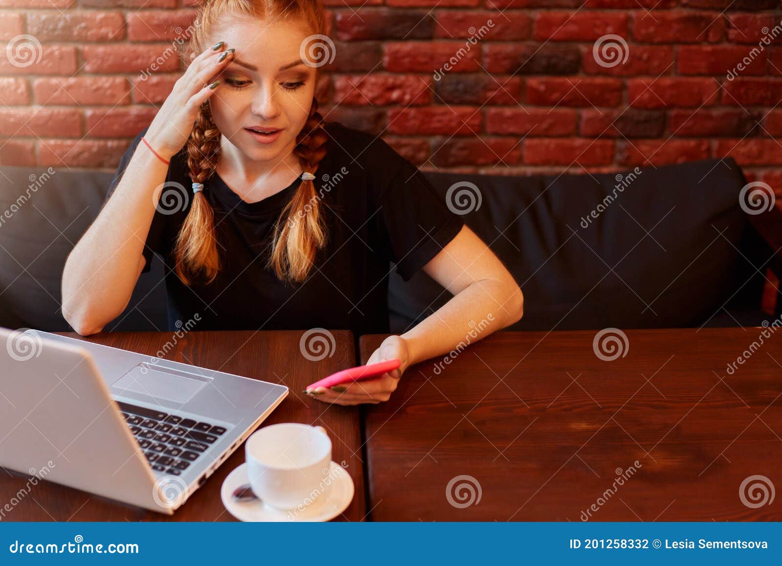 beautiful ginger caucasian girl using laptop computer and smart phone while sitting on sofa with astonish face emotion,reading