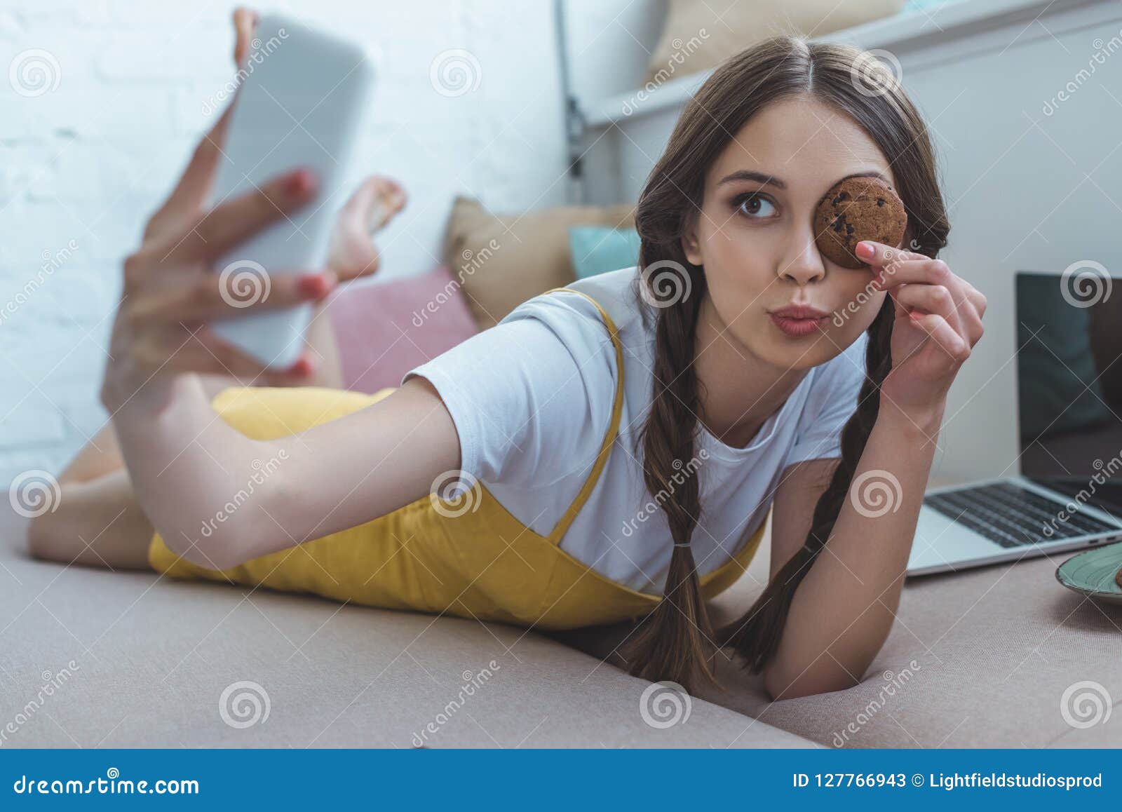 Beautiful Girl With Cookie Taking Selfie On Smartphone While Lying On 