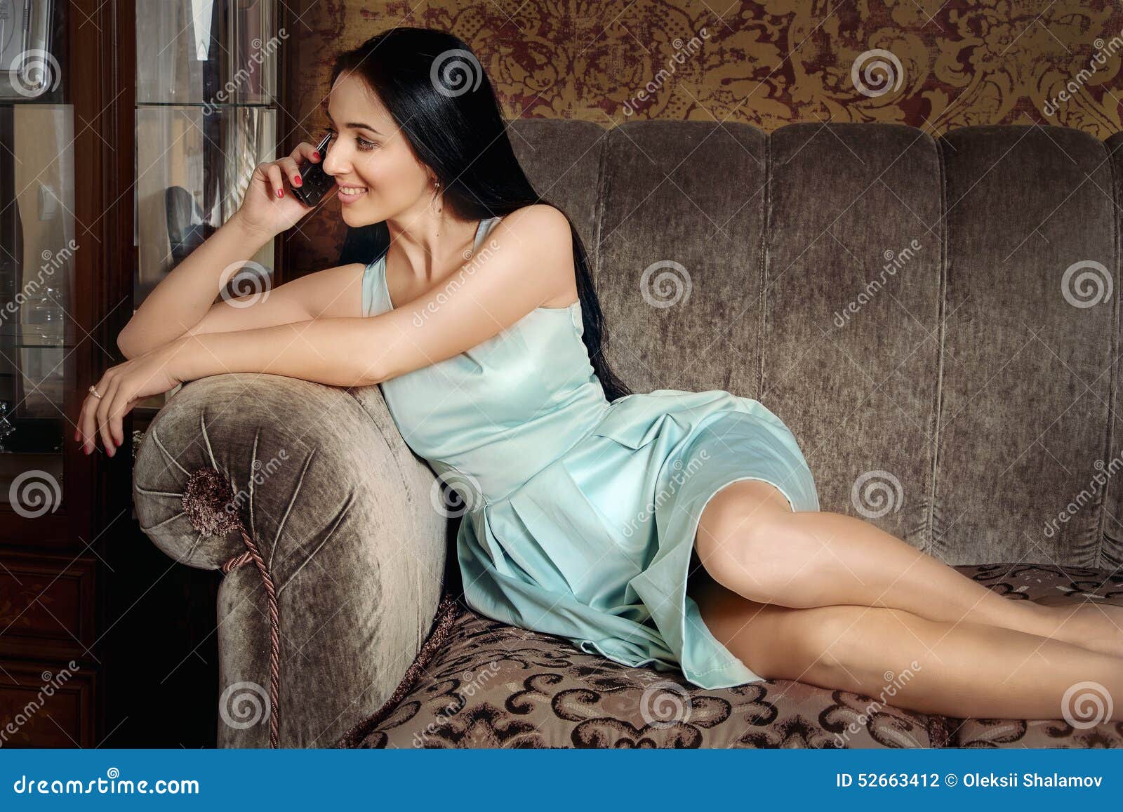 Beautiful Girl Lying On The Couch And Speaks By Phone Stock Photo