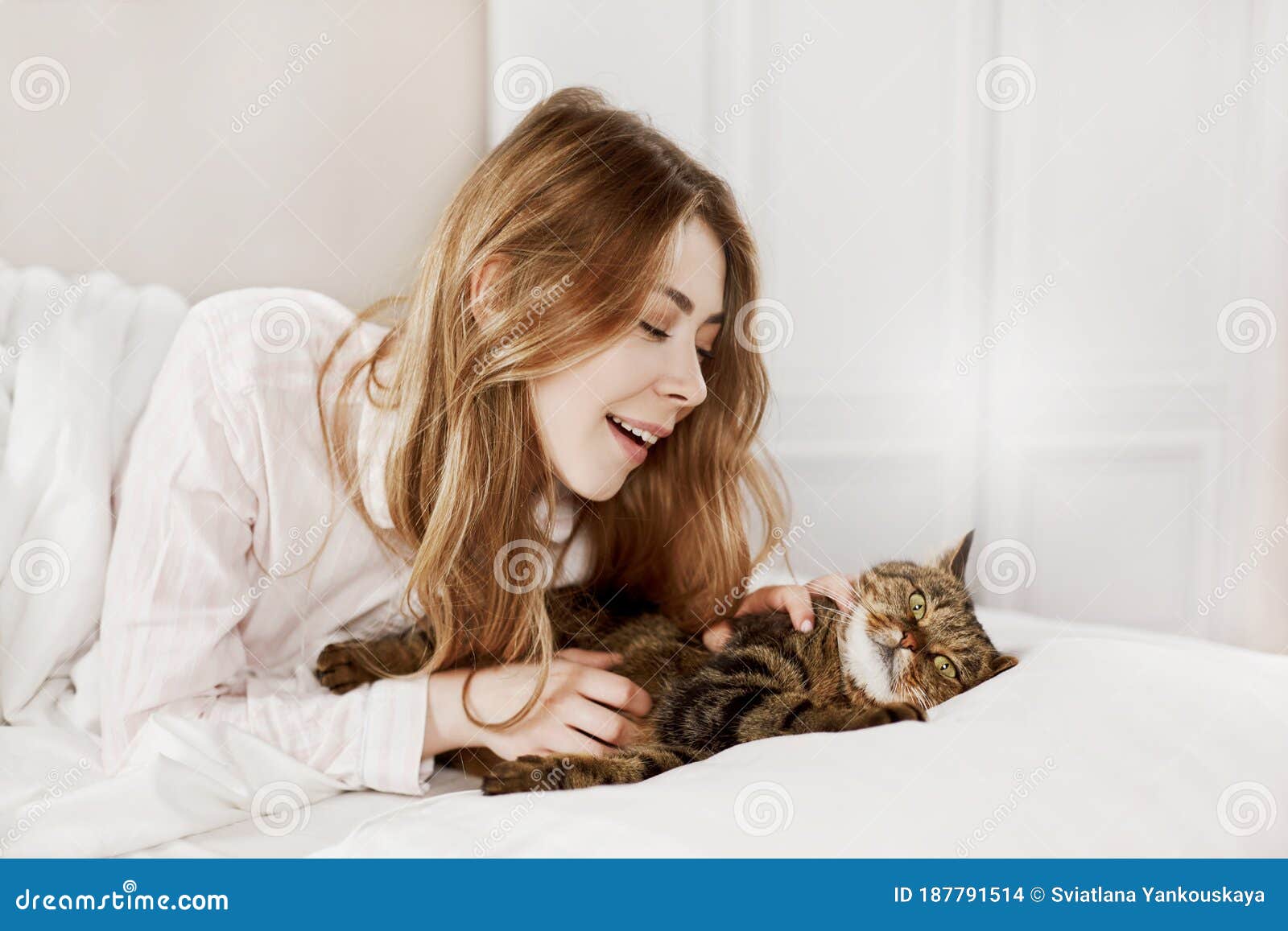 A Beautiful Girl Plays with Her Graceful Fluffy Cat on the Bed at Home ...