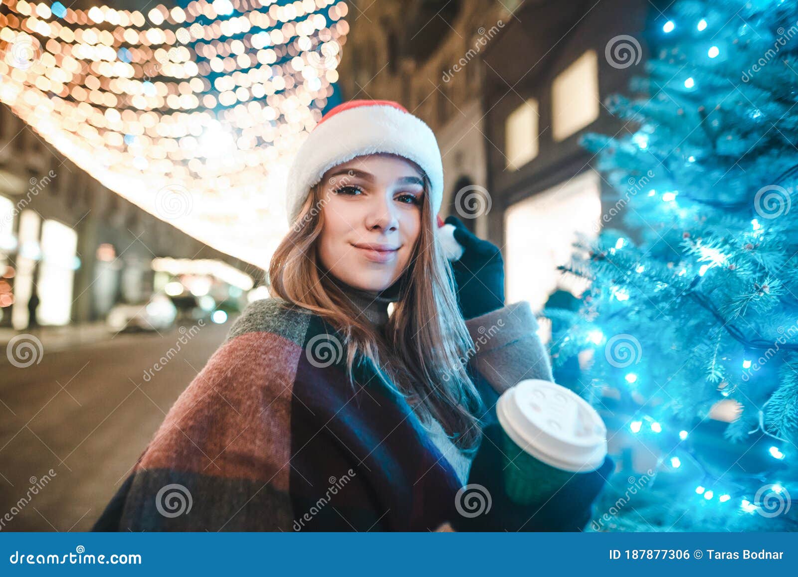 Beautiful Girl in a Santa Hat Stands Near a Christmas Tree on a Street ...