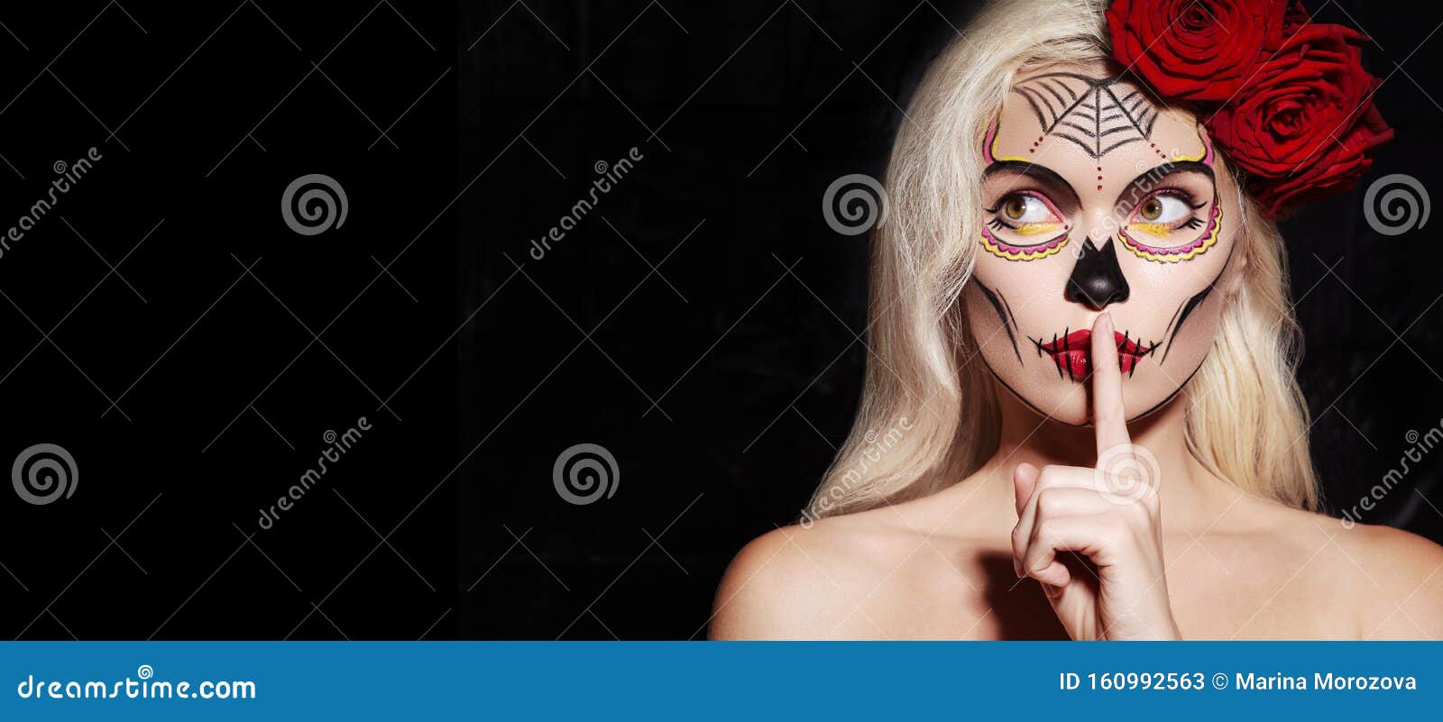 beautiful halloween make-up style. blond model wear sugar skull makeup with red roses. santa muerte concept