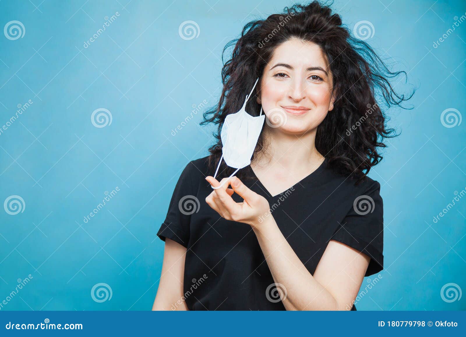 beautiful happy black haired woman taking off medical antiviral mask.