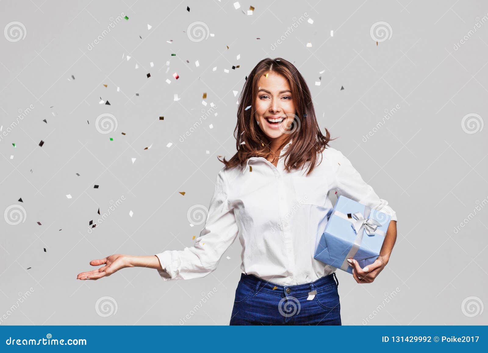 beautiful happy woman with gift box at celebration party with confetti falling everywhere on her.