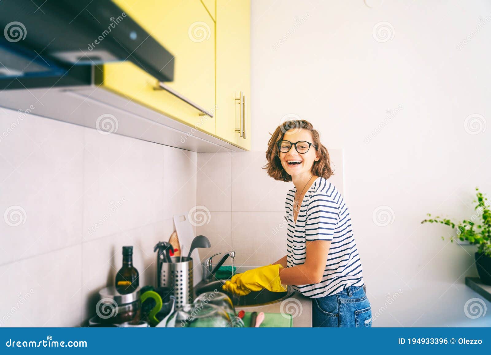 Beautiful young woman washing dishes in kitchen Stock Photo by ©belchonock  37724727