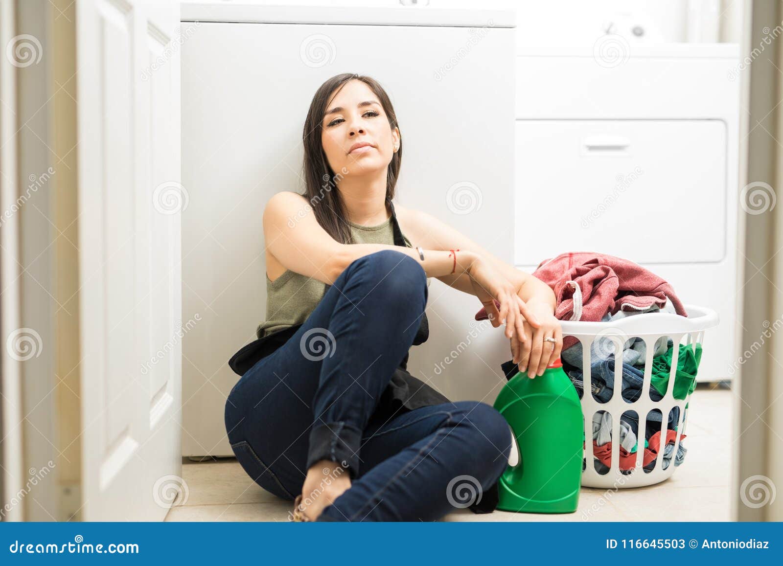 Bored Young Woman Sitting On Floor In Laundry Room Stock Image