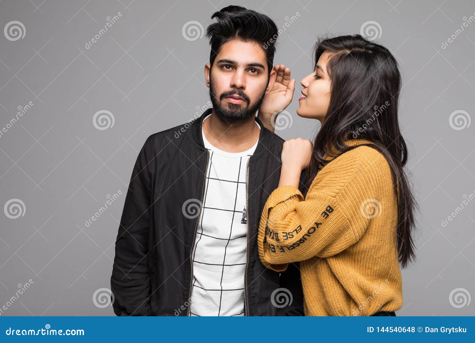 Beautiful Indian Woman Whispering To Boyfriends Ear Isolated on Gray Background Stock Photo pic