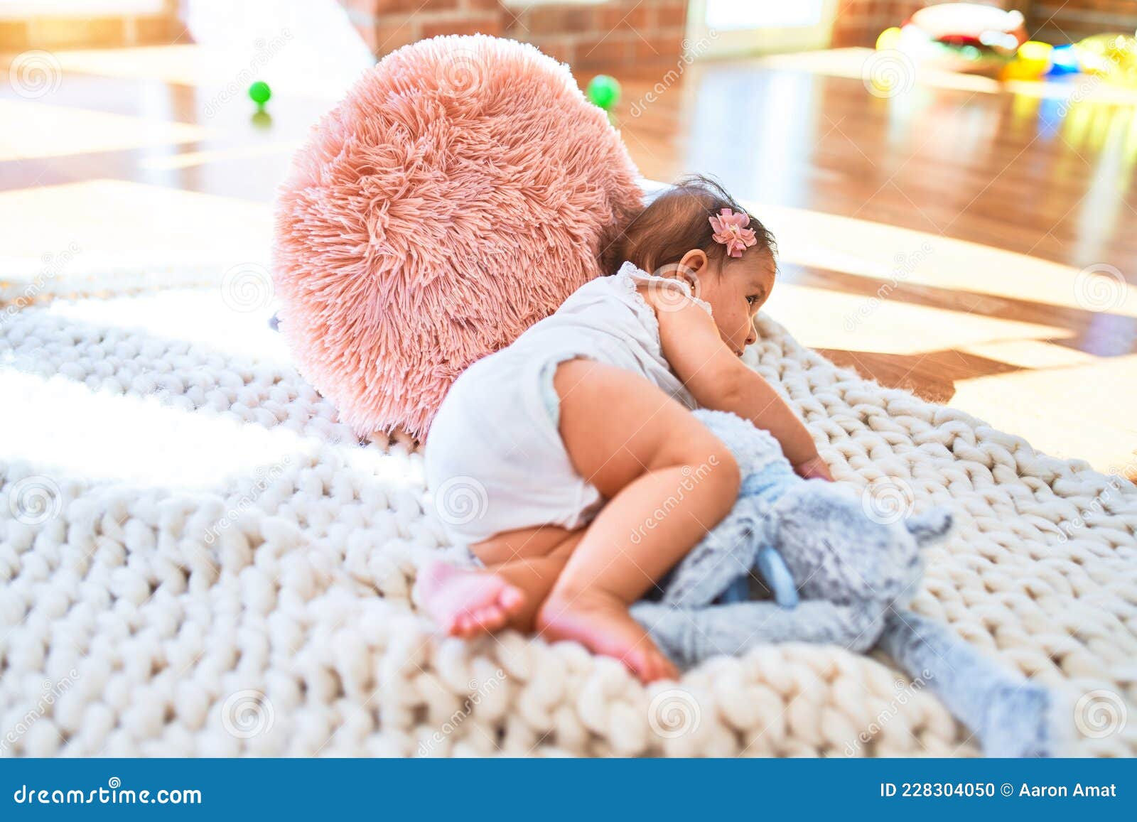 beautiful infant happy at kindergarten around colorful toys lying on blacket