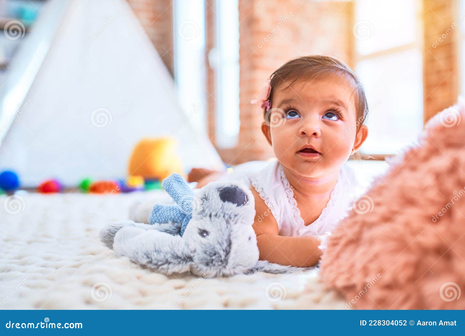 beautiful infant happy at kindergarten around colorful toys lying on blacket