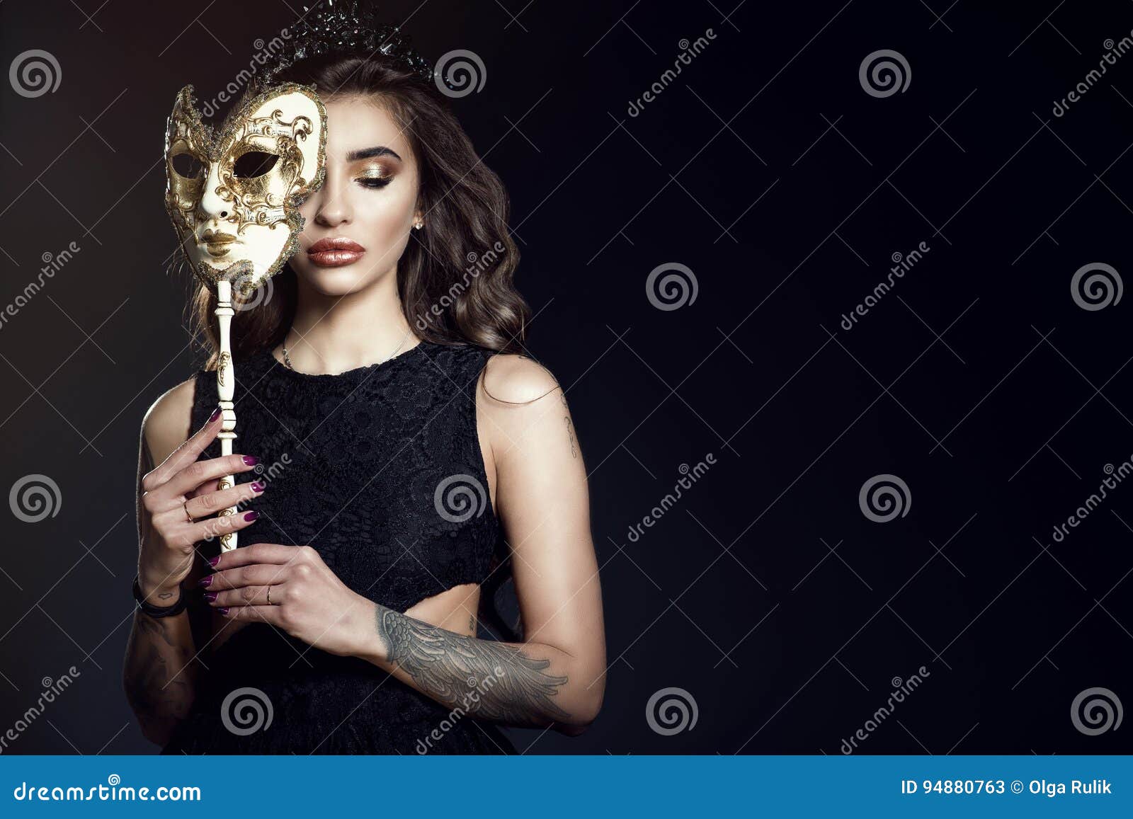 beautiful lady with closed eyes hiding the half of her face behind the venetian mask