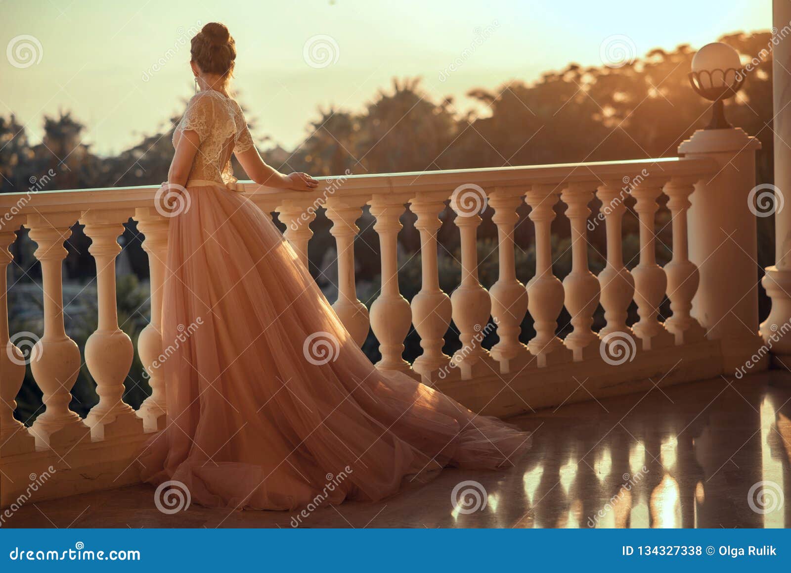 beautiful lady in luxurious ballroom dress with tulle skirt and lacy top standing on the large balcony