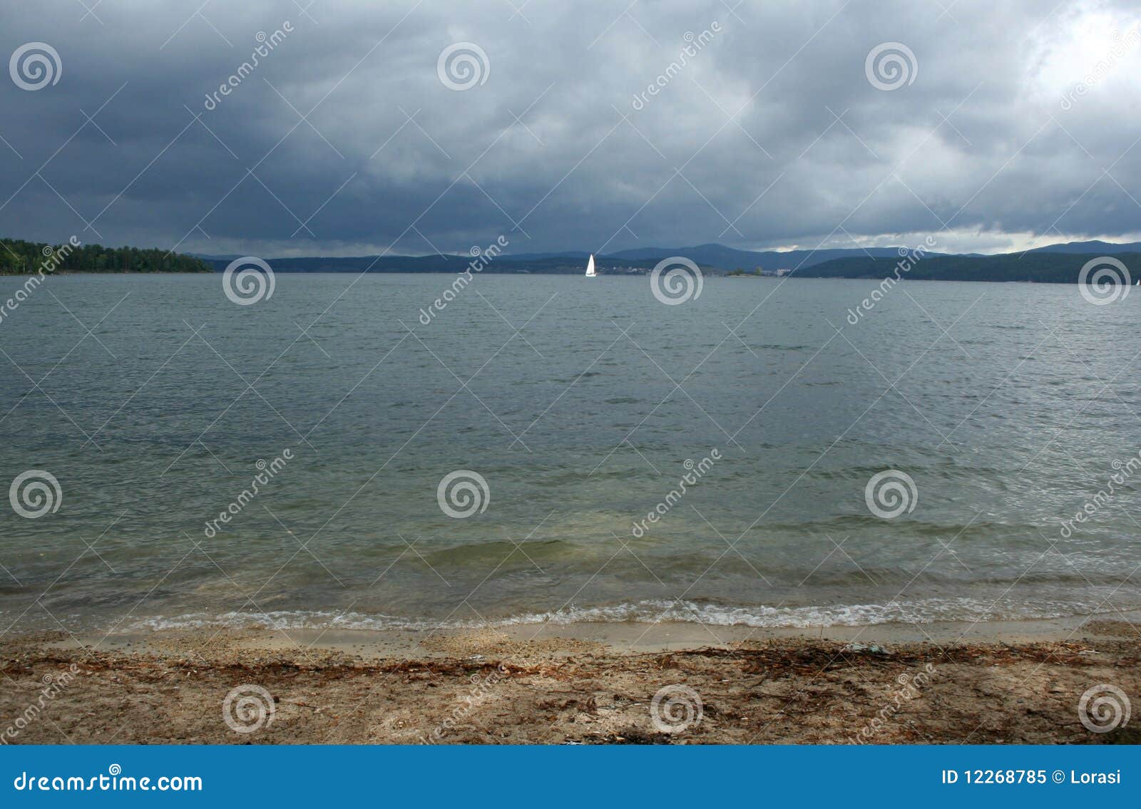 Beautiful lake and yaht on the background of dark cloudy sky
