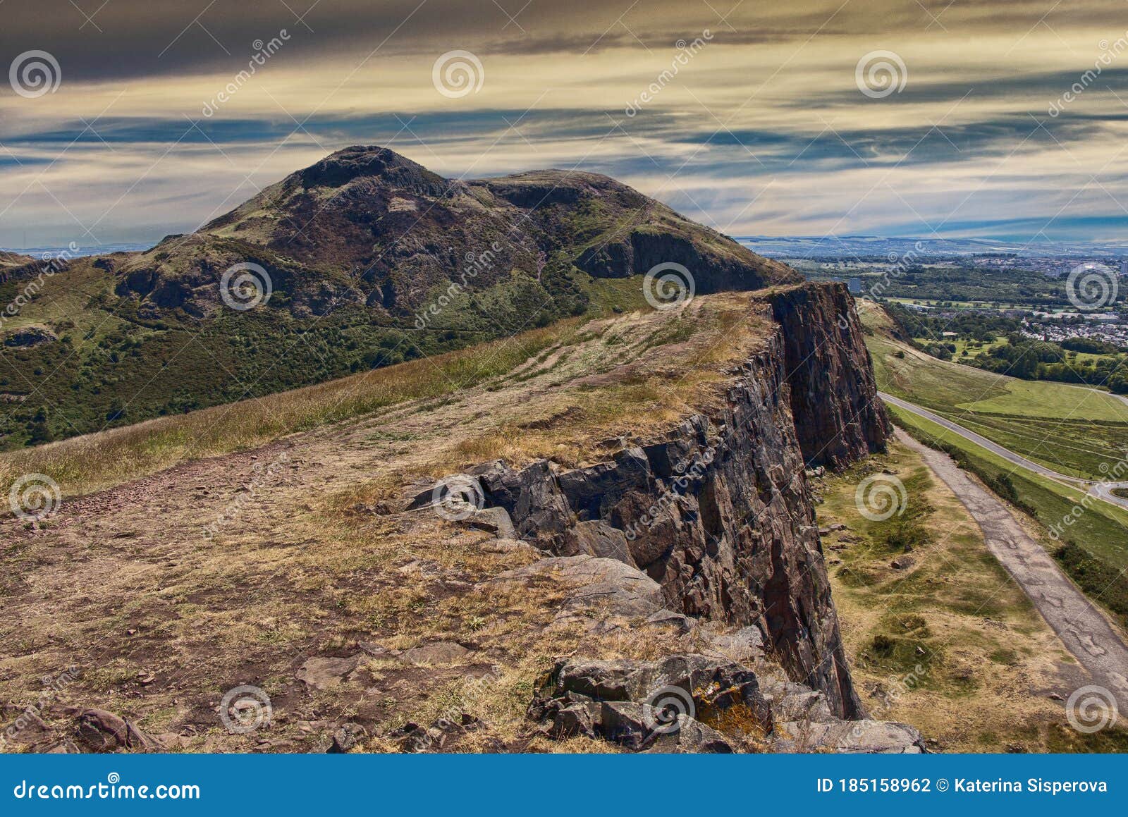 beautiful landscape of arthur`s seat mountain in scotland with path on the cliff and edinburgh city in the background