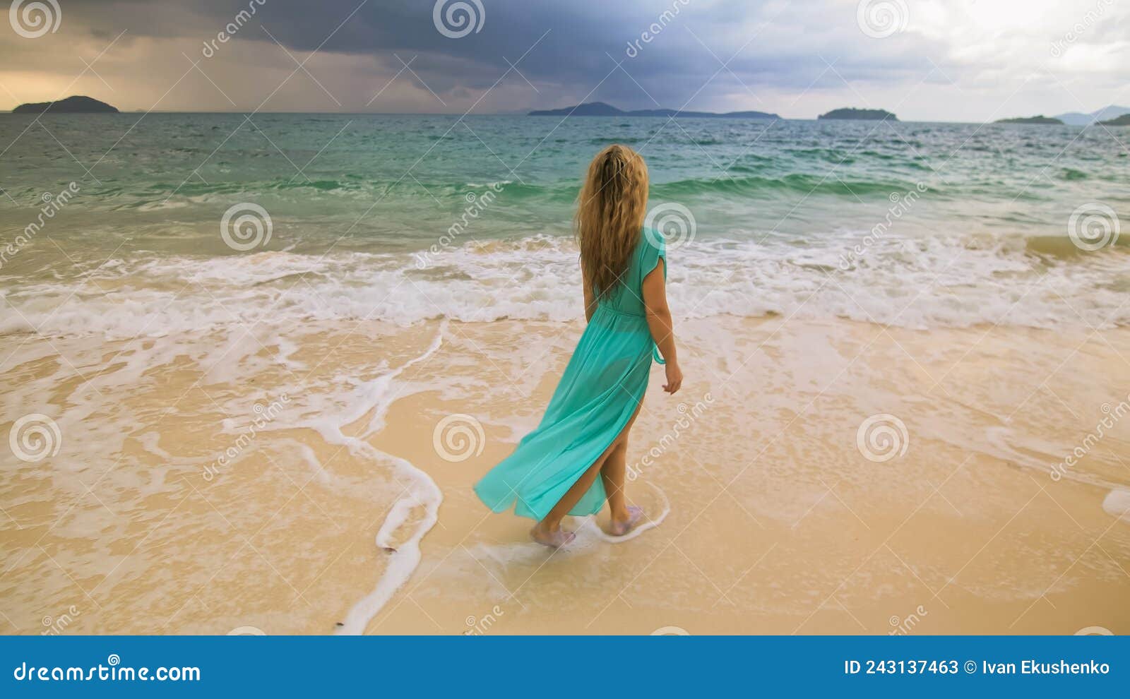 Woman Walks To The Stormy Cloudy Ocean On Sand Beach Girl In Blue