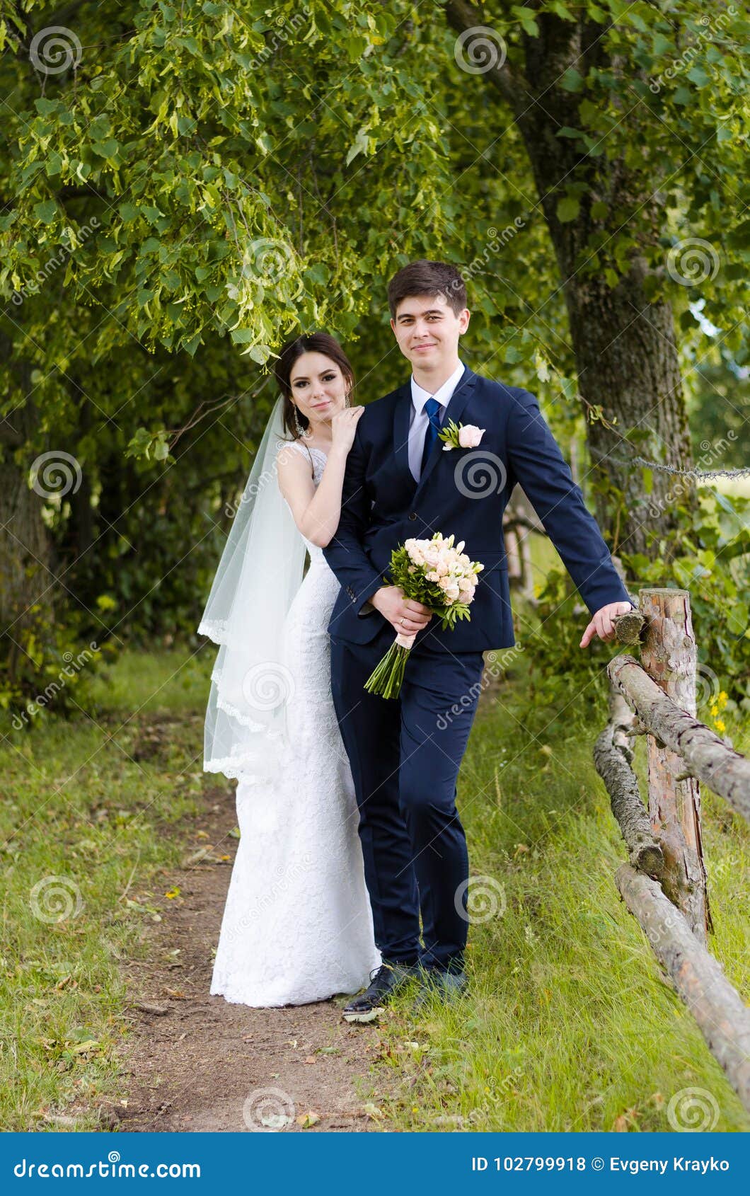A Beautiful Married Couple in Wedding Dresses, Posing for a Photo Shooting  in an Belarusian Village Near the Fence, with a Wedding Stock Photo - Image  of green, beautiful: 102799918