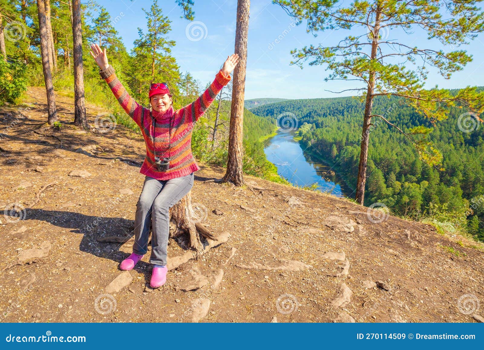 Beautiful Mature Women Sits On A High Rock Above The River And Admires The Big Aisian Cliffs