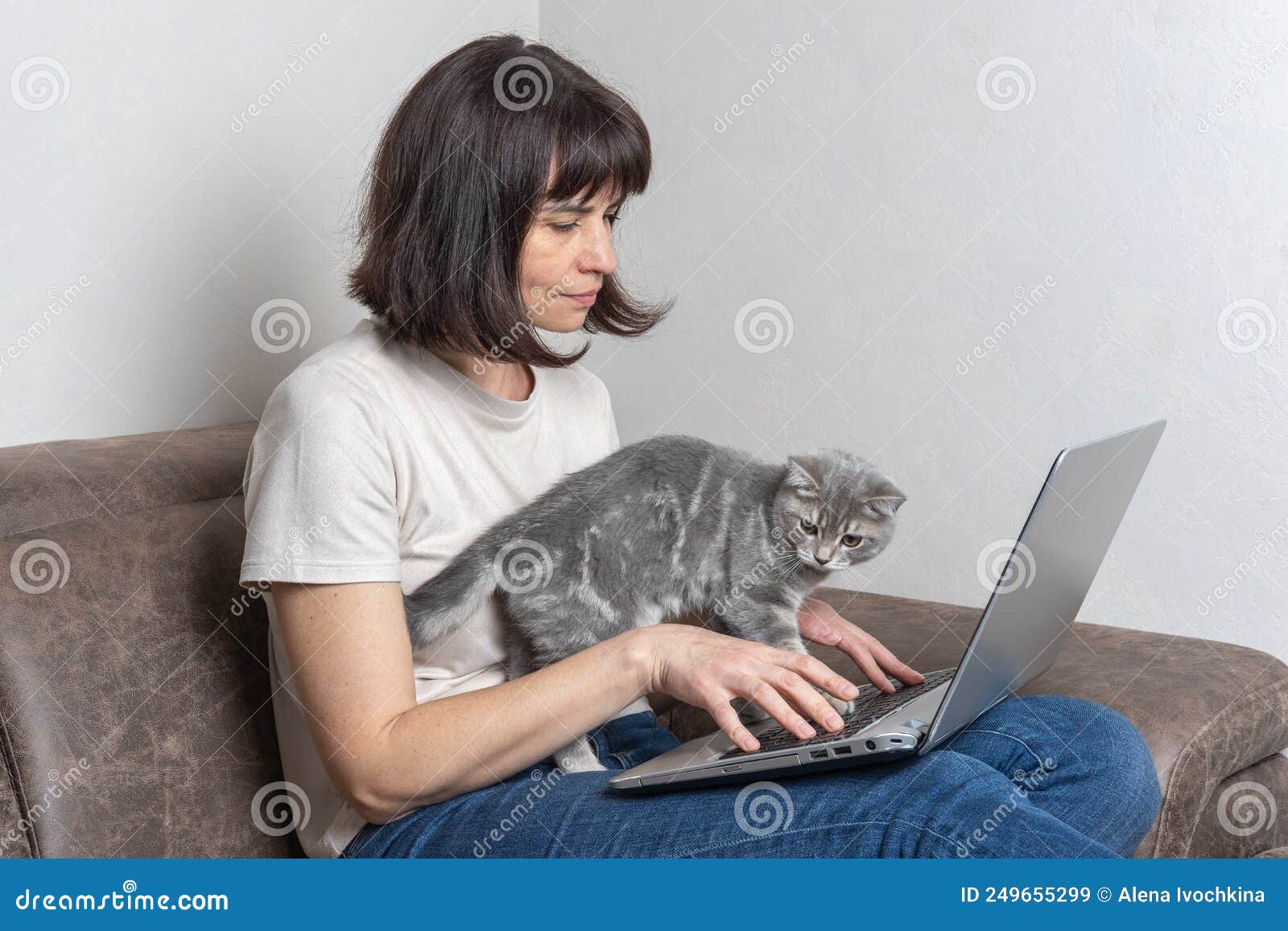 beautiful middle aged woman with a cutecat works at home on a laptop. middle-aged woman works remotely.