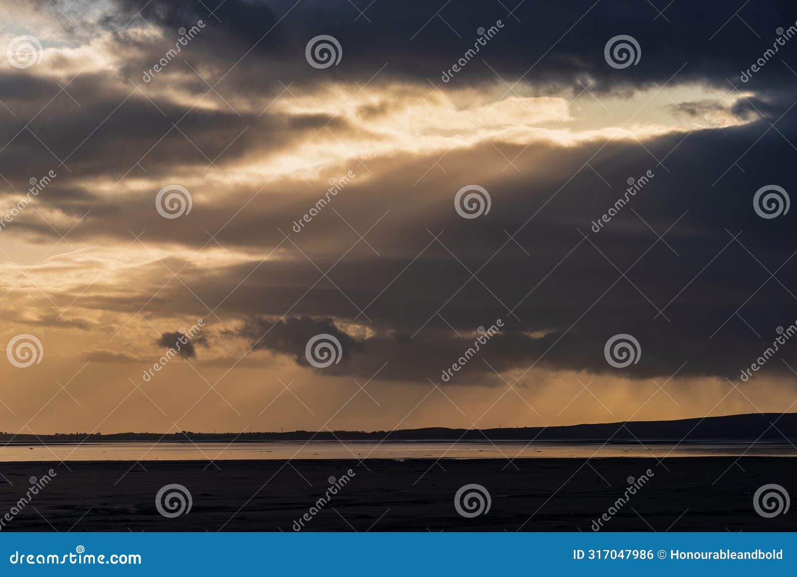 beautiful moody storm skies over ocean landscape with distant heavy rainfall