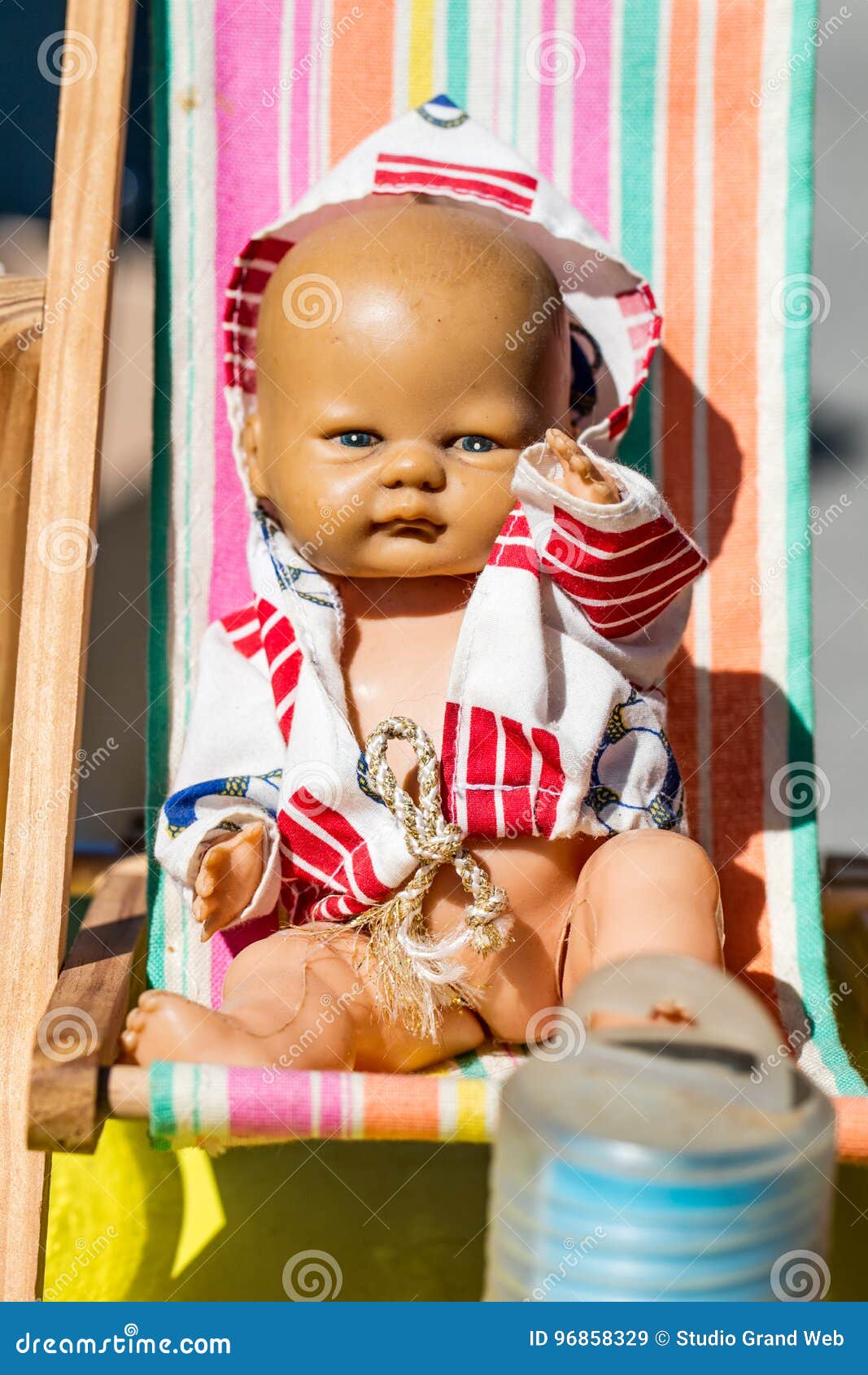 beautiful old summer doll on small deckchair for childhood nostalgia