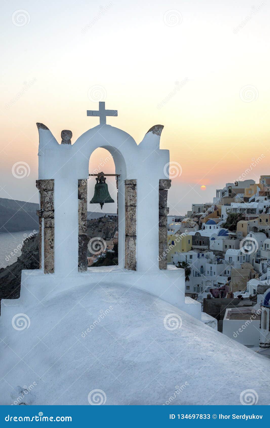 arch with a bell, white houses and church with blue domes in oia or ia at golden sunset, island santorini, greece. - immagine