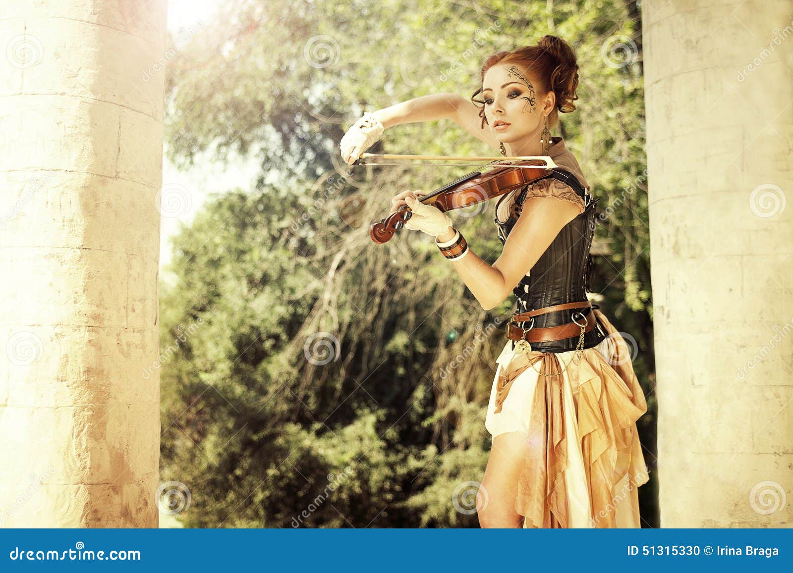 beautiful redhair woman with body art on her face playing on violin outdoors.