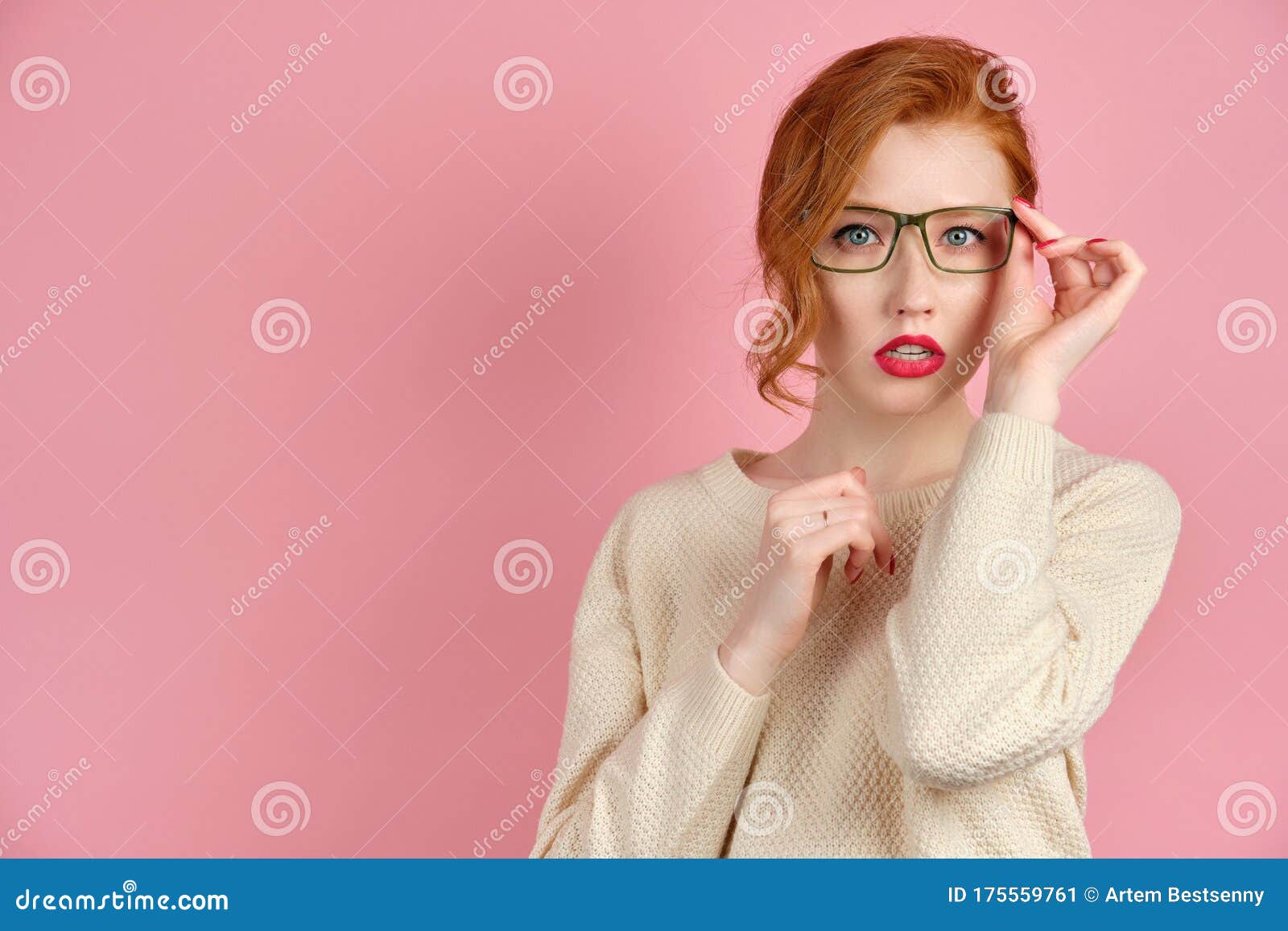 Beautiful Redhead Girl With Red Lipstick And Manicure Stands On A Pink Background And Adjusting