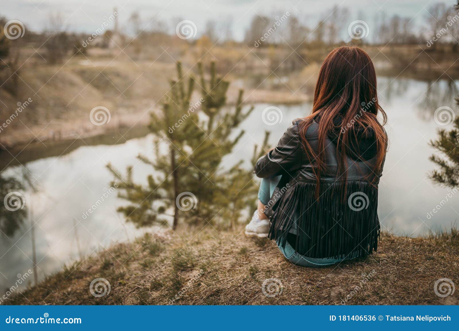 Beautiful Sad Girl Sitting On The Lake In Jeans, Looking Into The Distance  And Thinking About The Meaning Of Life. The Concept Of Stock Photo - Image  Of Gloomy, Looking: 181406536