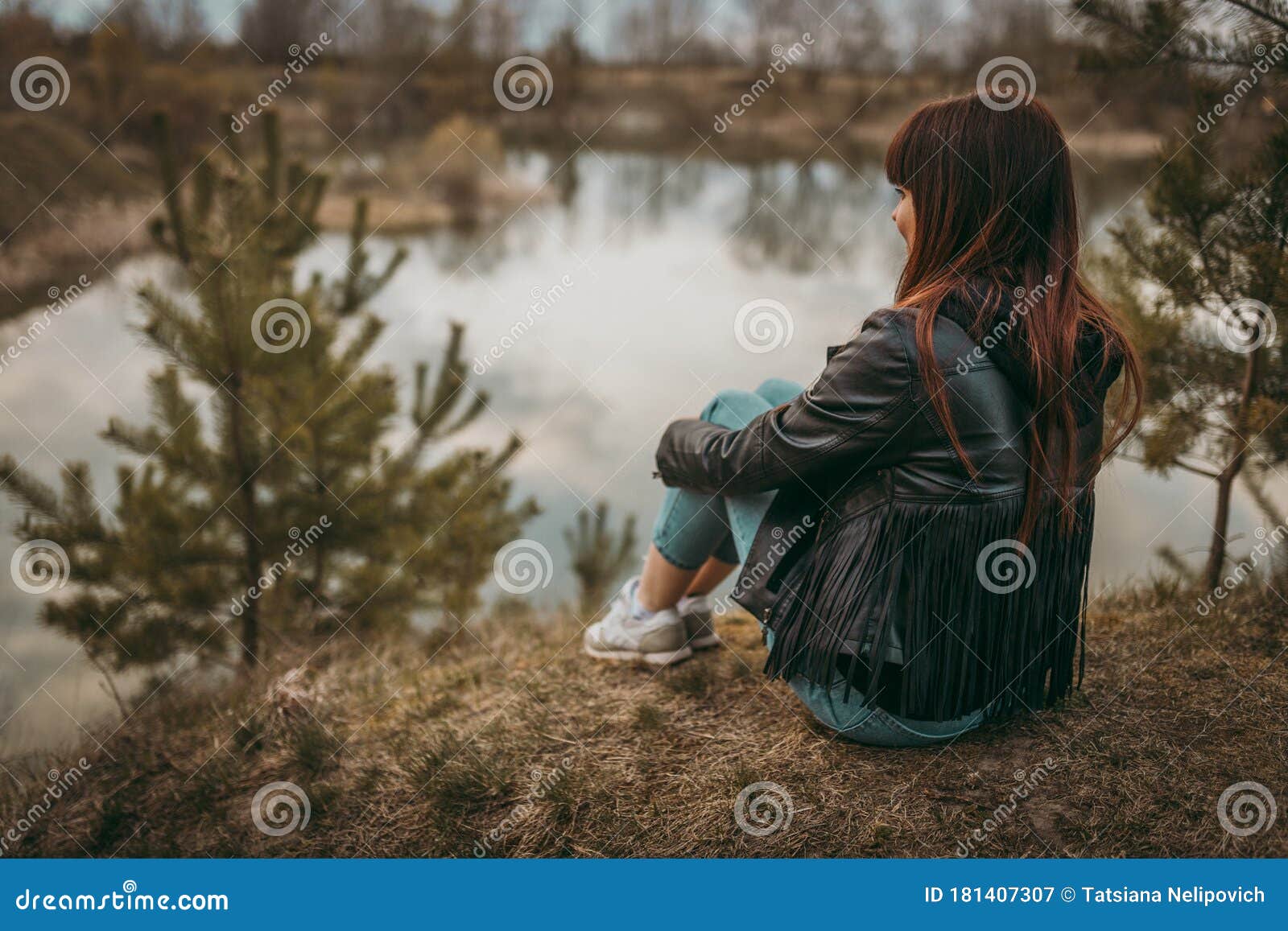 Beautiful Sad Girl Sitting on the Lake in Jeans, Looking into the ...