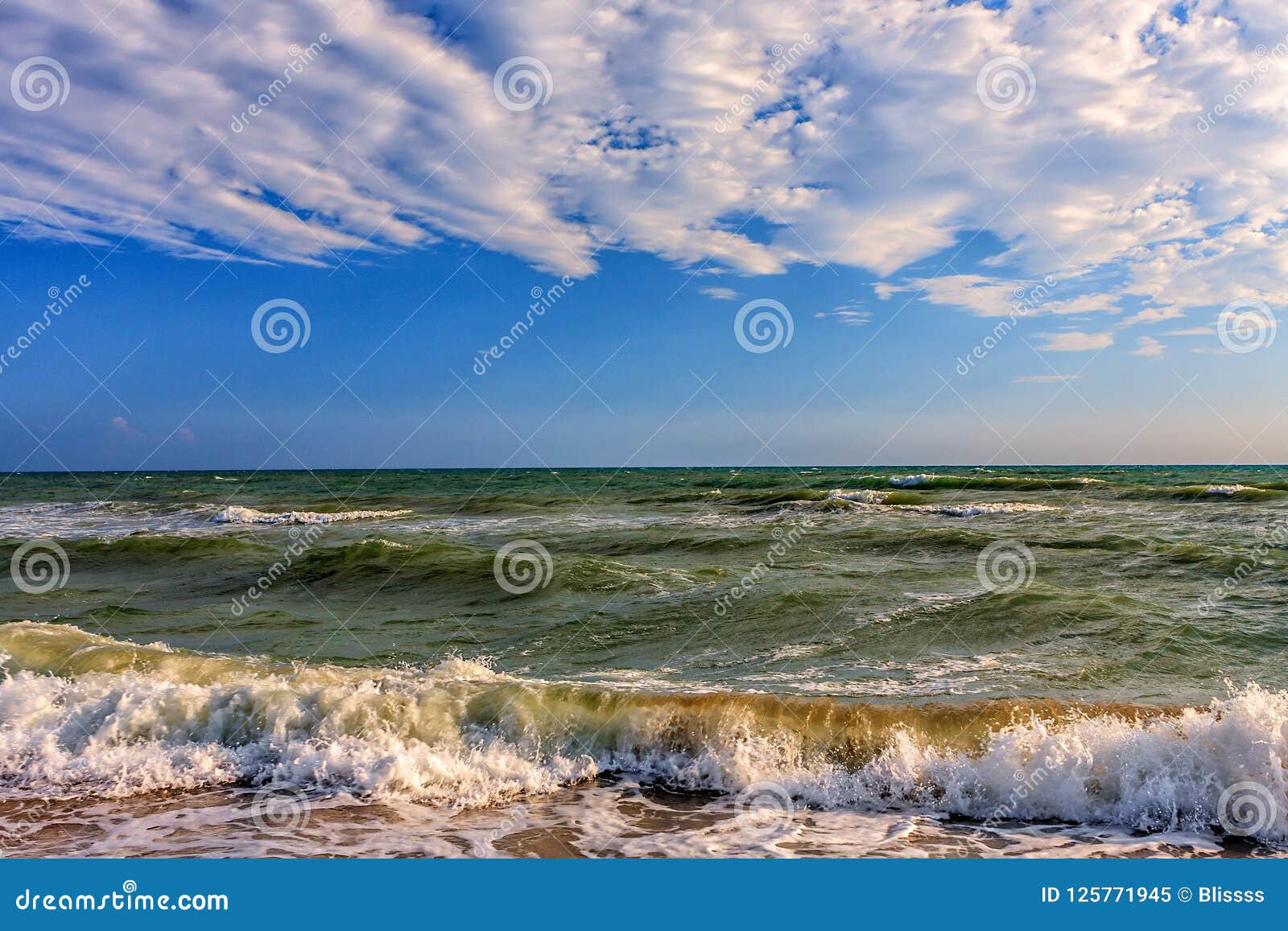 scenic seascape with surfing waves breaking onto sandy black sea shore by anapa on sunny day