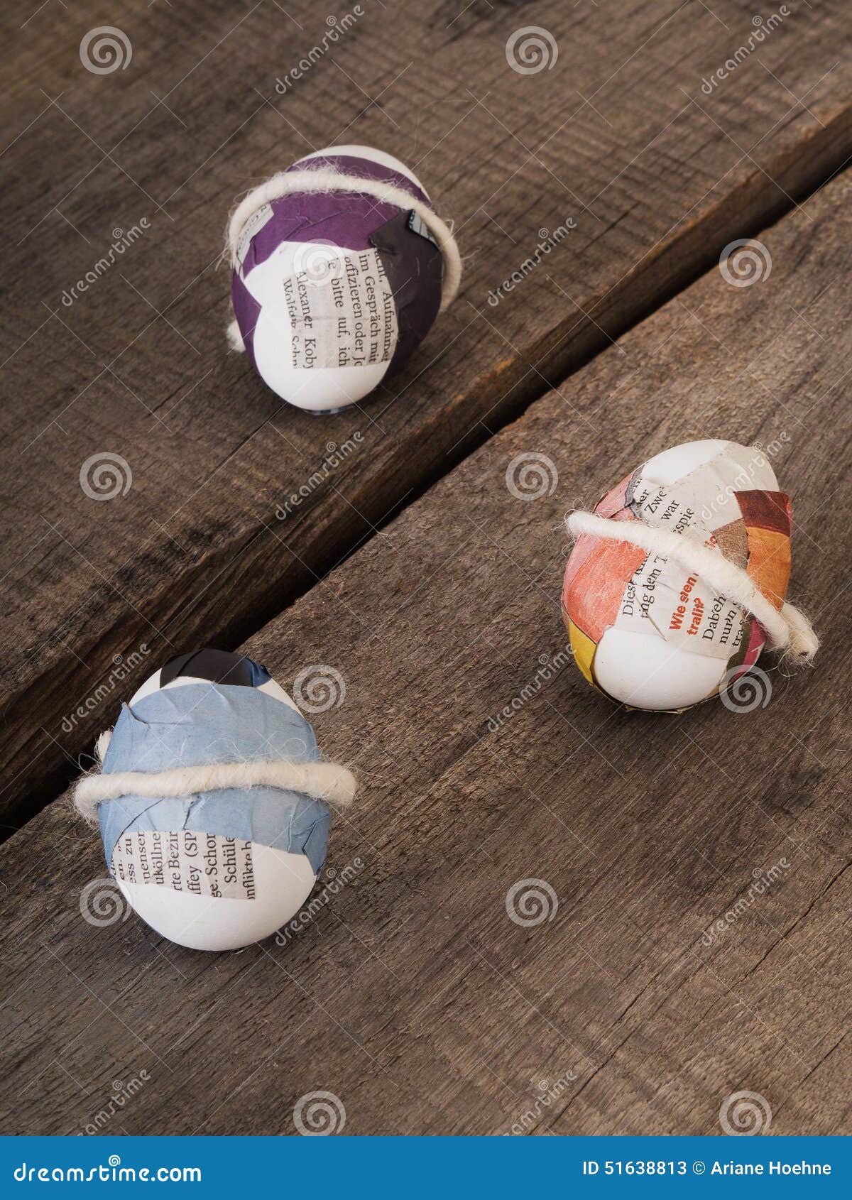 Beautiful selfmade easter eggs. Three selfmade easter eggs sticked with newspaper on a wooden table