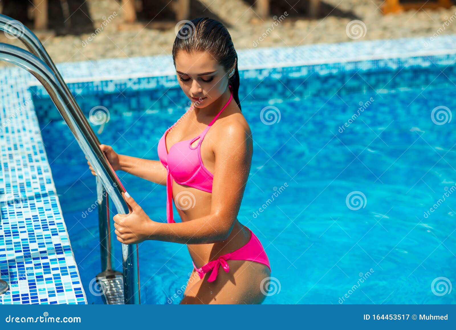 Happy woman swimming in pool in red swimsuit with loose long hair