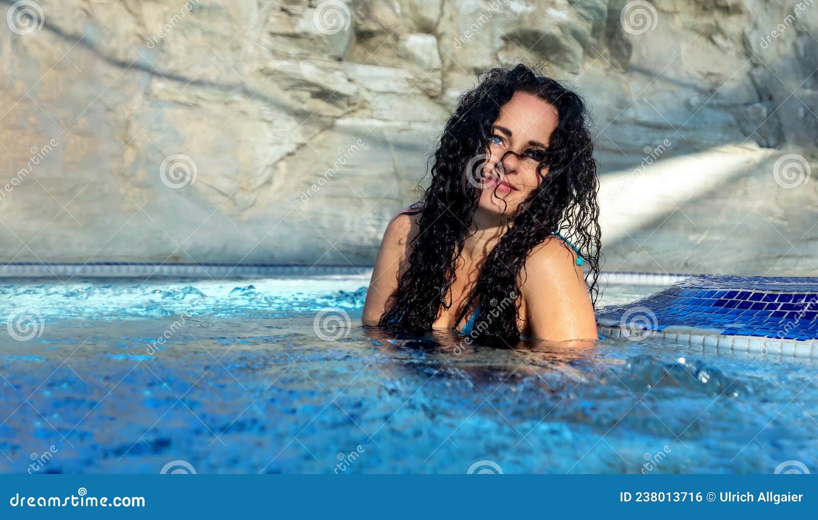 beautiful sexy portrait of mature woman with dark curly hair relaxes contend happy in holidays summer sun in the blue spa wellness