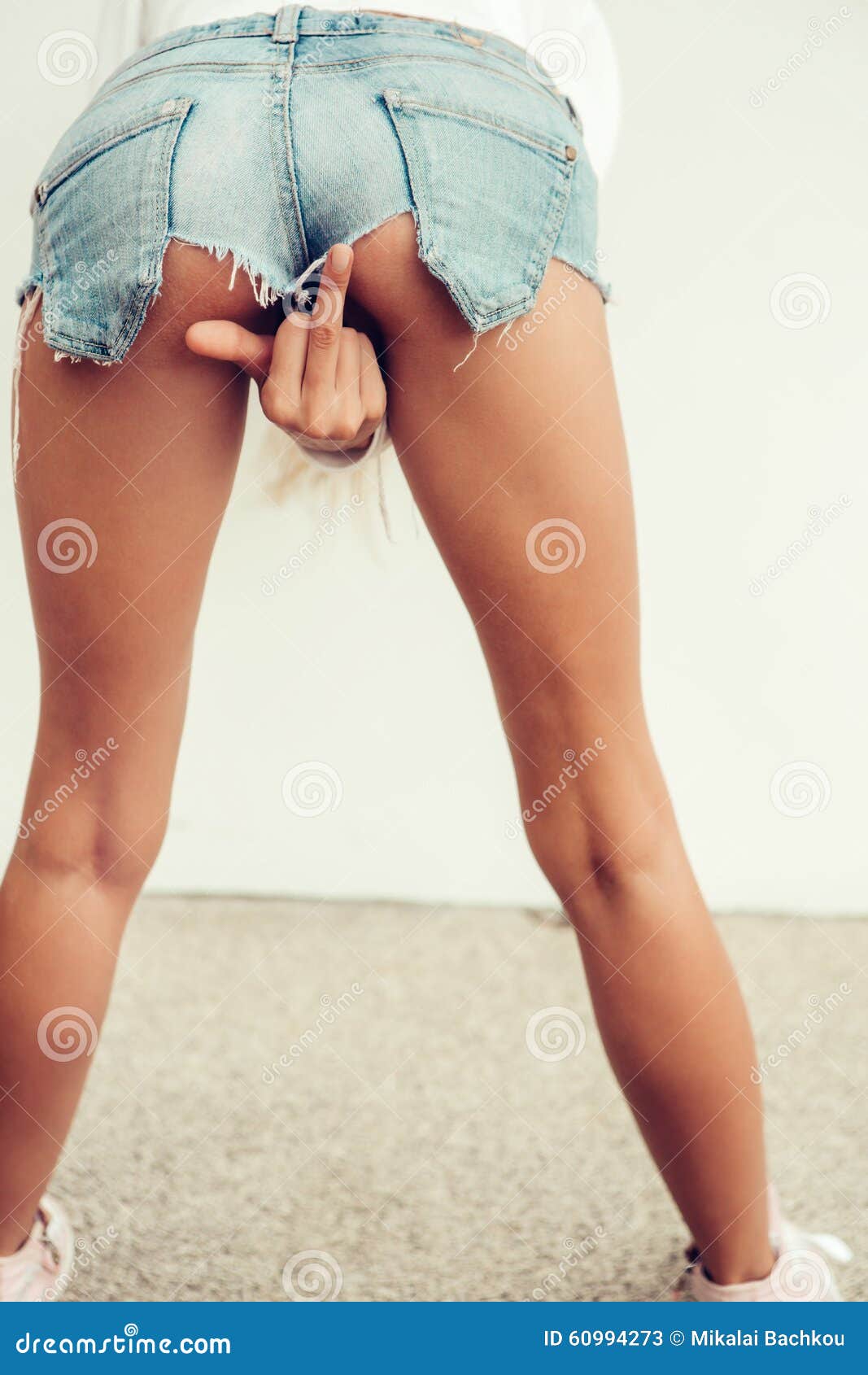 Beautiful Young Woman in Mini Jeans Shorts Shows an Obscen Stock Image picture