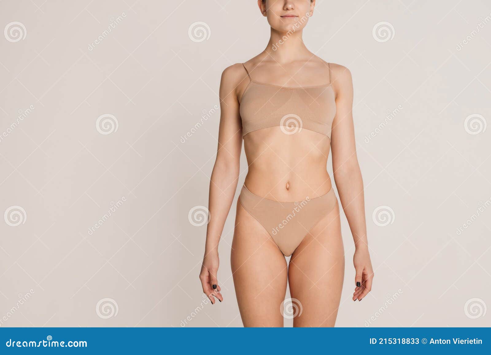 Beautiful Slim Female Body in Nude Color Underwear Over Grey