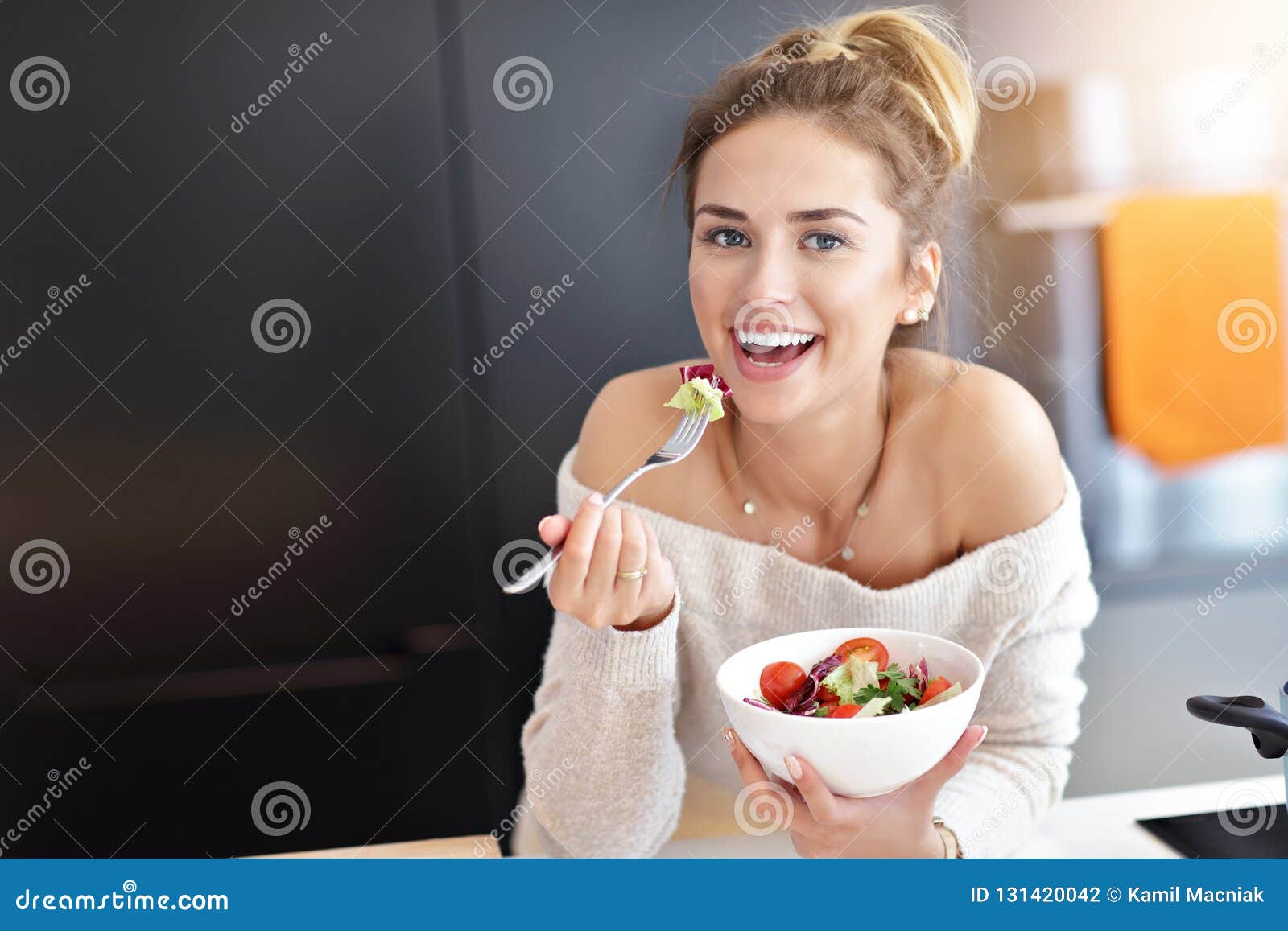 beautiful smiling woman eating fresh organic vegetarian salad in modern kitchen