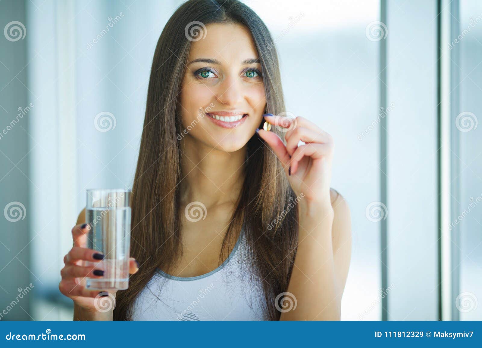 beautiful smiling woman taking vitamin pill. dietary supplement