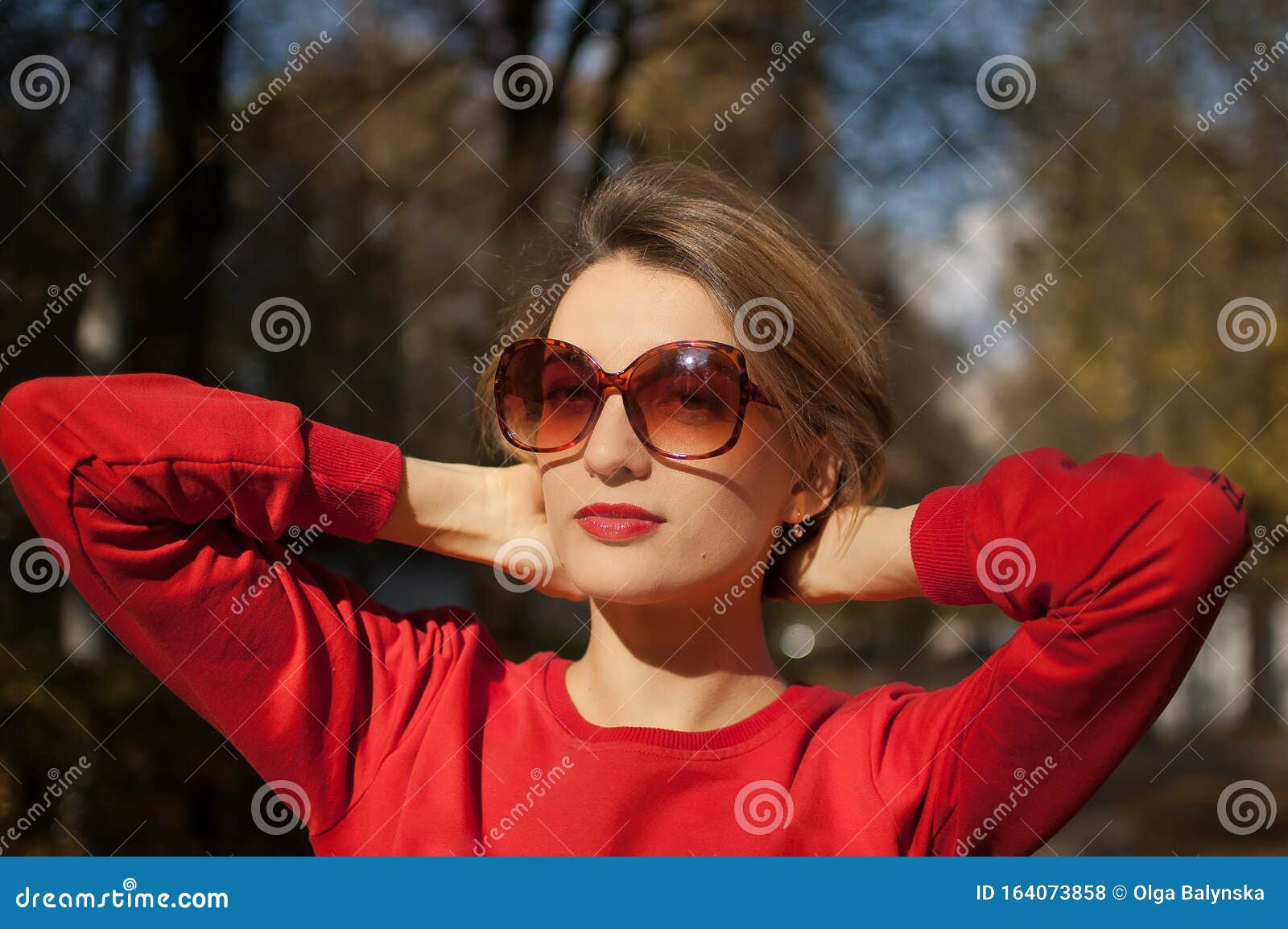 Beautiful Smiling Woman Wearing A Sunglasses And Red Sweater Is Posing