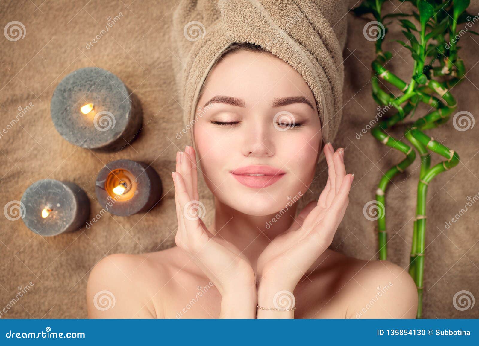 beautiful spa woman with a towel on her head lying and touching face skin. skincare